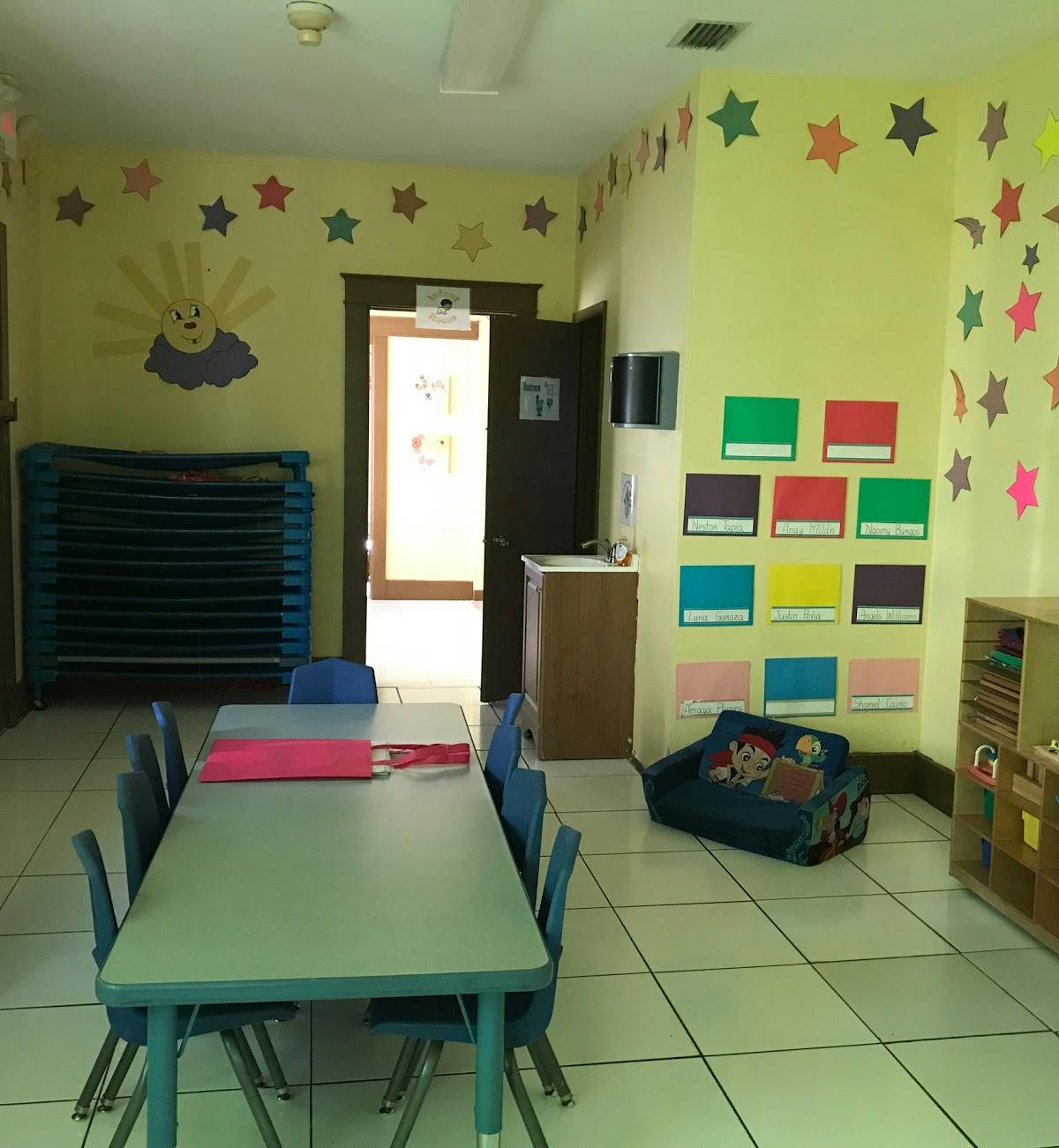 Classroom with small table and chairs, cots, and decorated walls