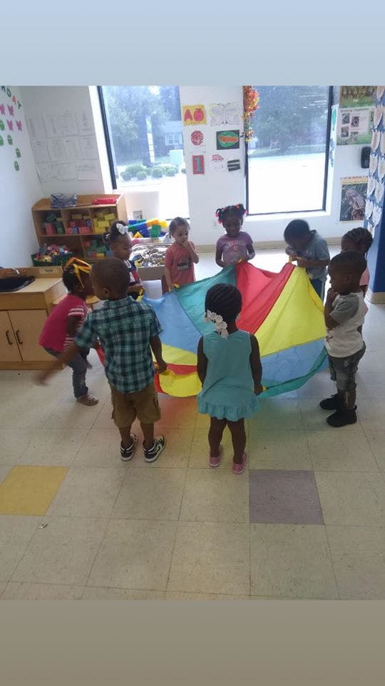Children playing with a colorful parachute in a classroom