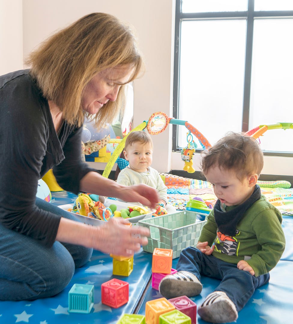 Person playing with two children and colorful blocks