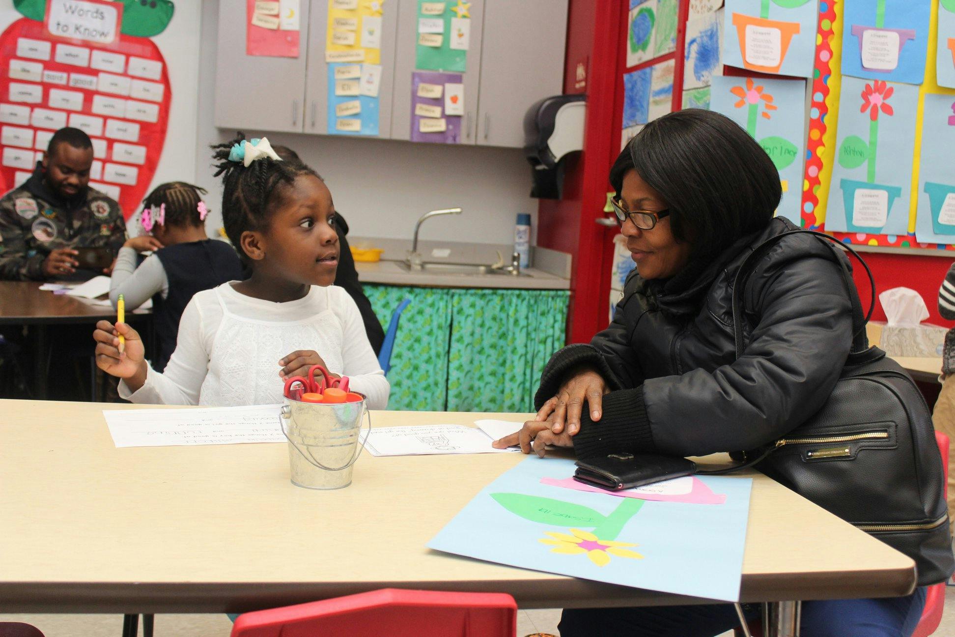 Adult and child sitting at a table in a classroom