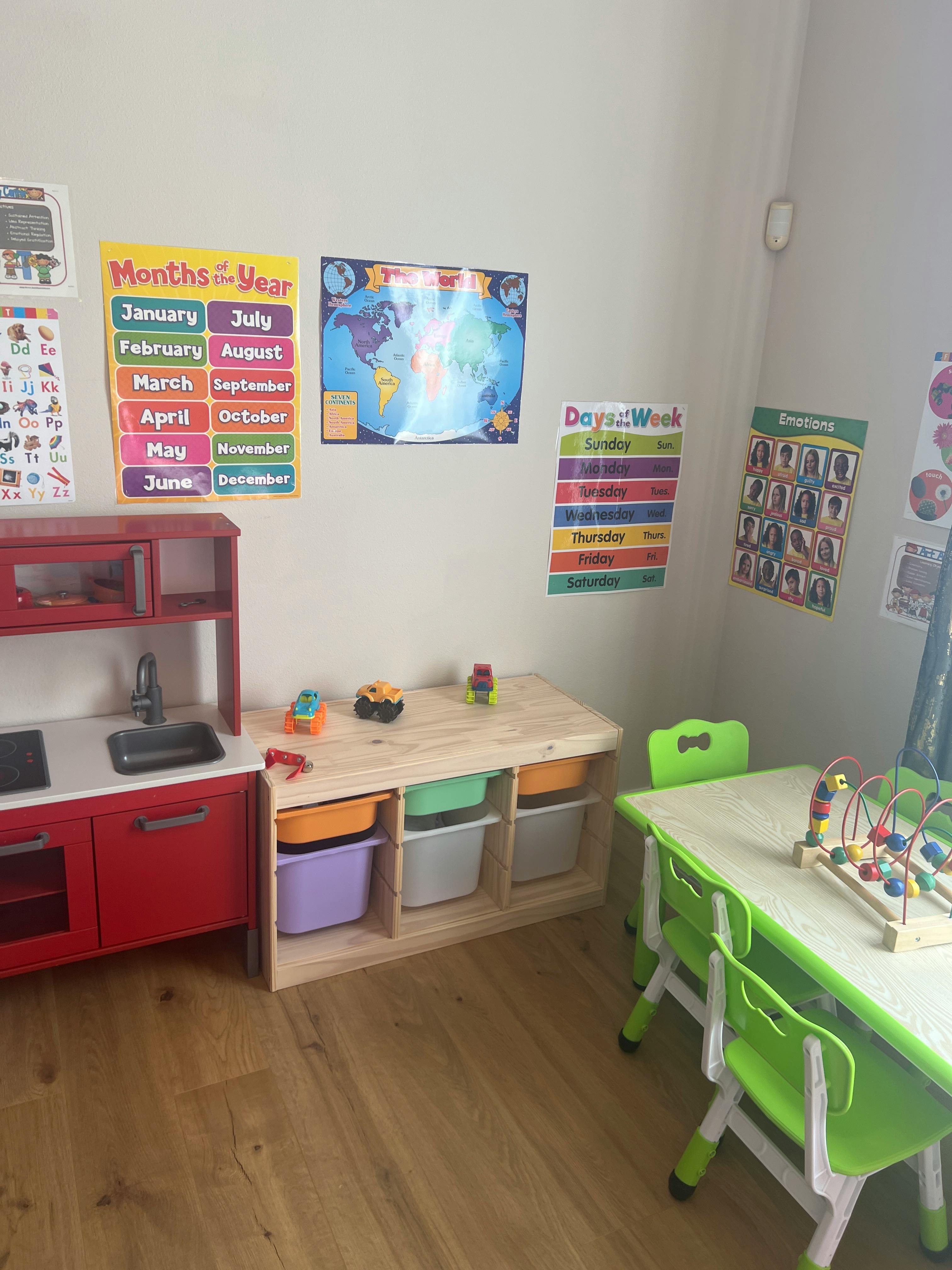 Play kitchen and storage unit with colorful bins in a classroom