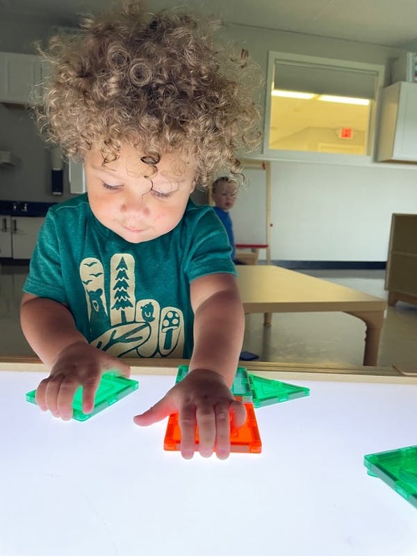 Child playing with colorful translucent blocks on a light table