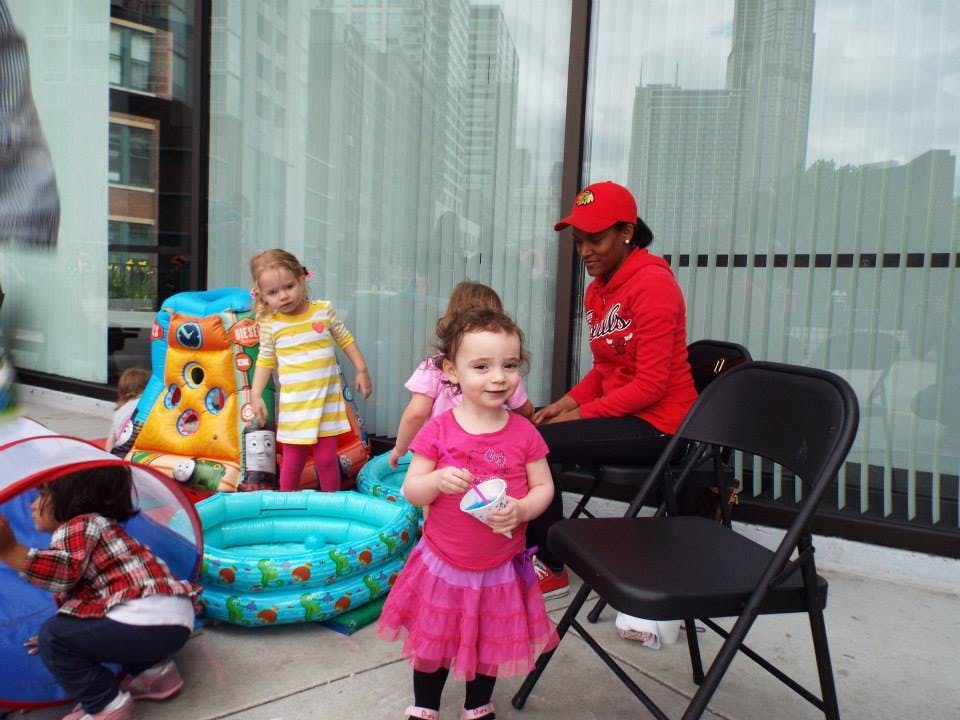 Children playing with toys and an inflatable pool, person sitting nearby