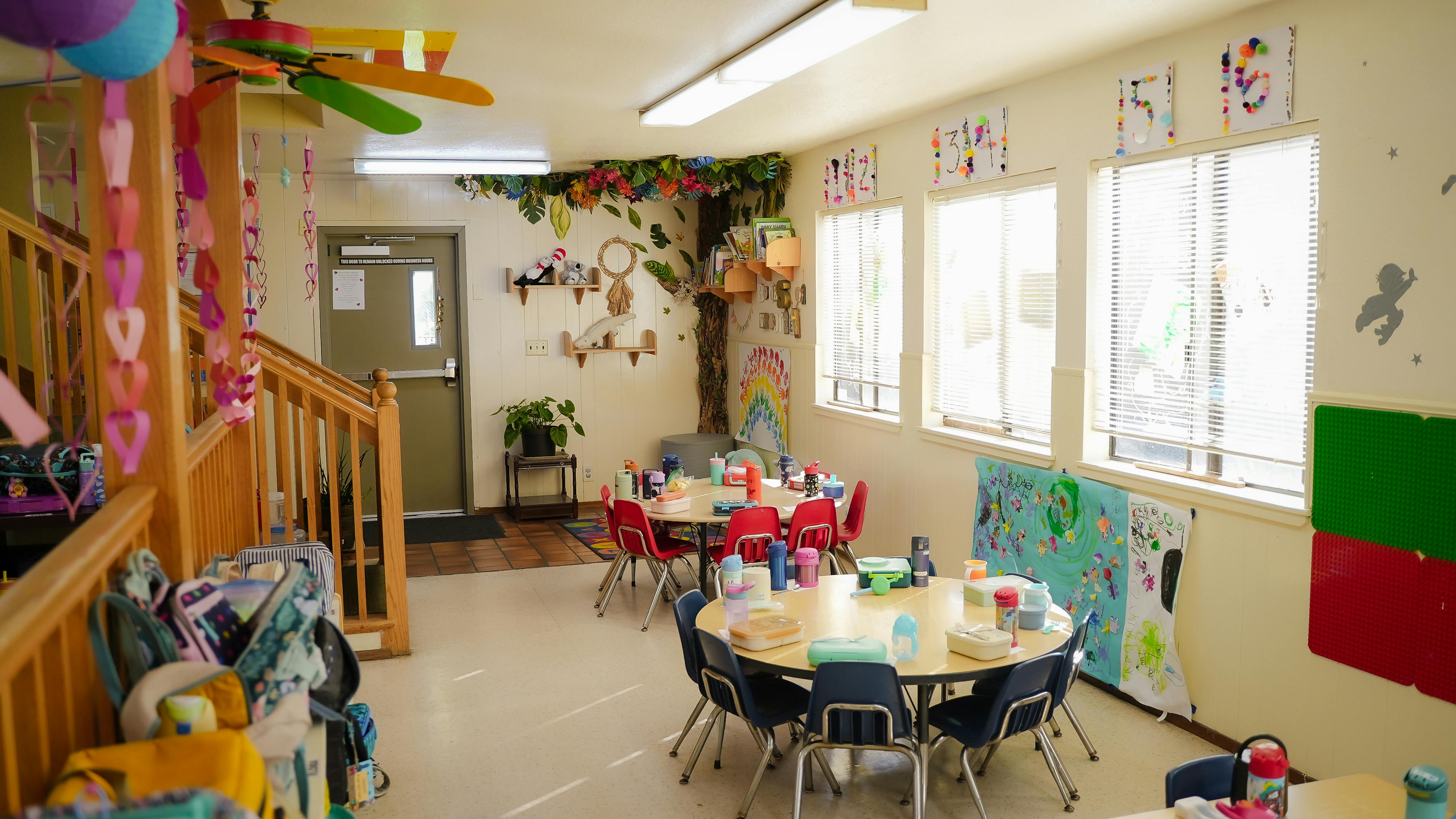 Classroom with round tables, small chairs, and educational wall decorations