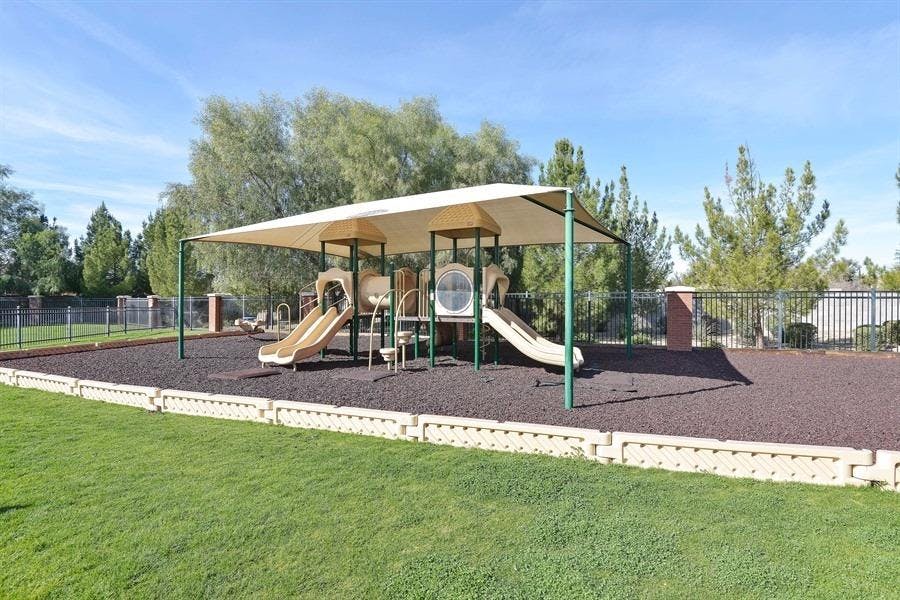 Playground with slides and climbing structures under a shade canopy
