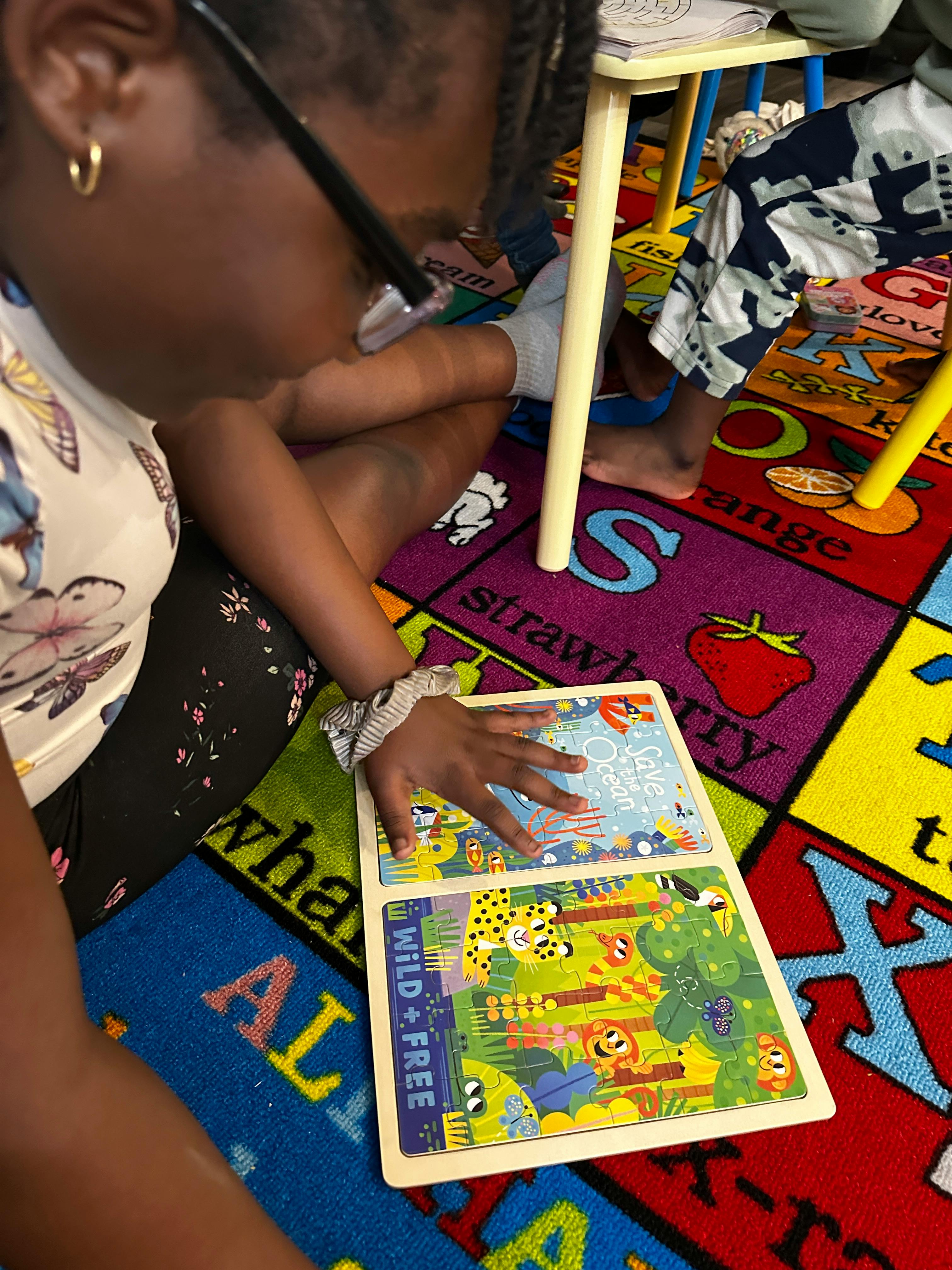 Child sitting on a colorful rug, hand on an open book with illustrations