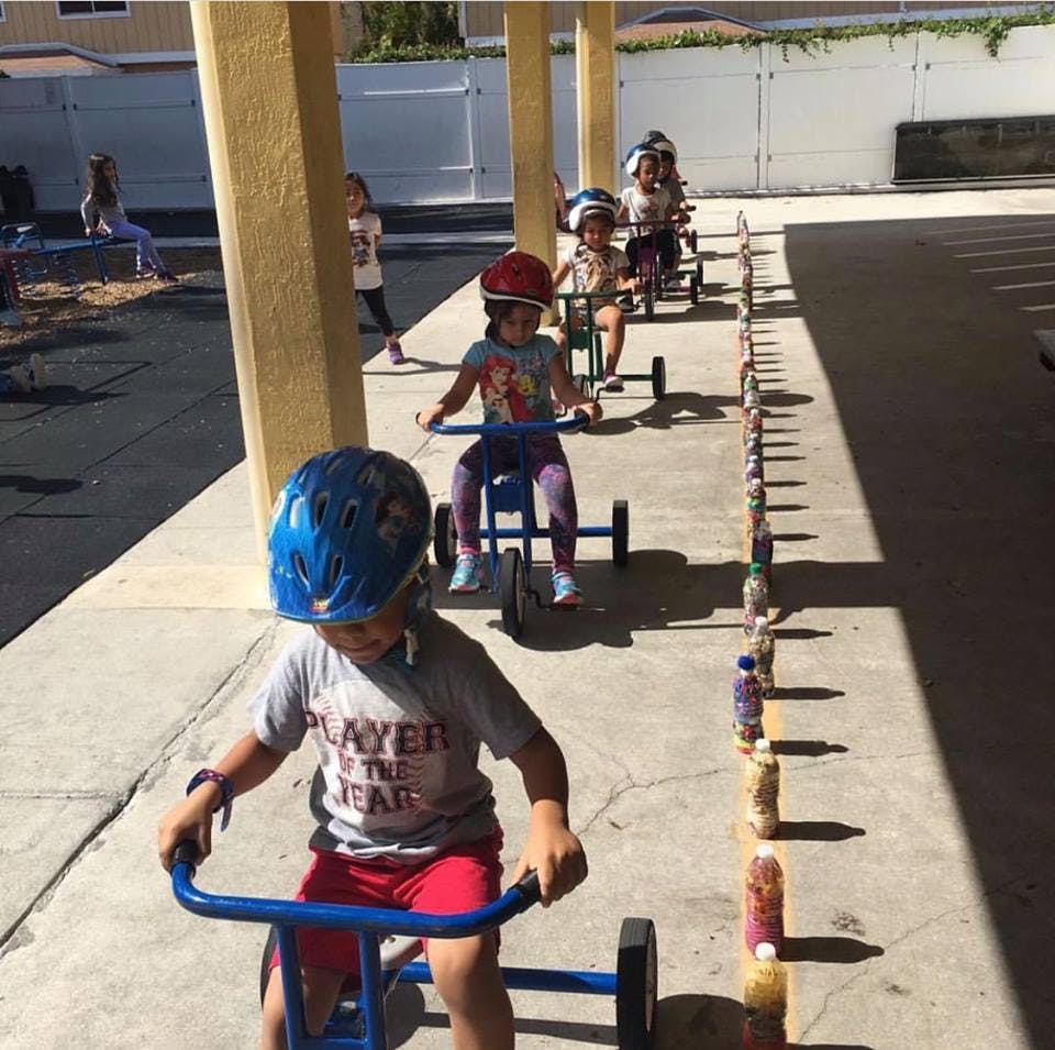 Children wearing helmets riding tricycles outdoors