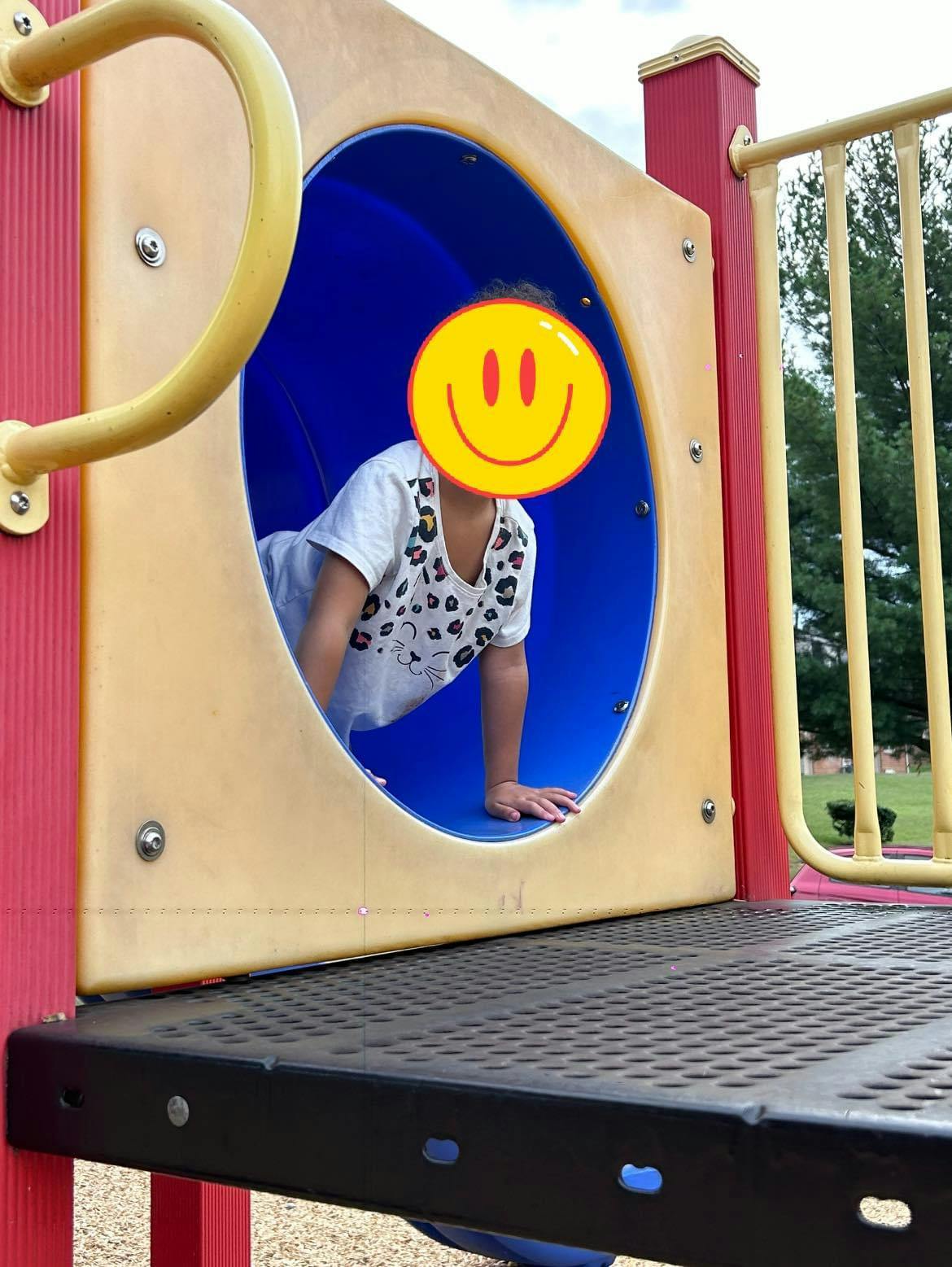Child crawling through a blue tunnel on a playground