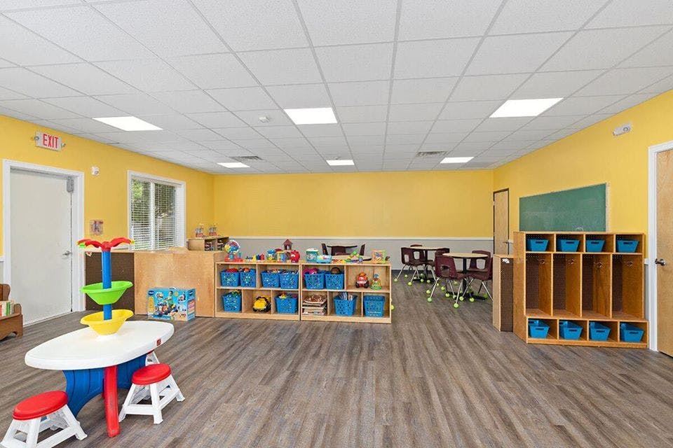 Empty classroom with small tables and storage shelves