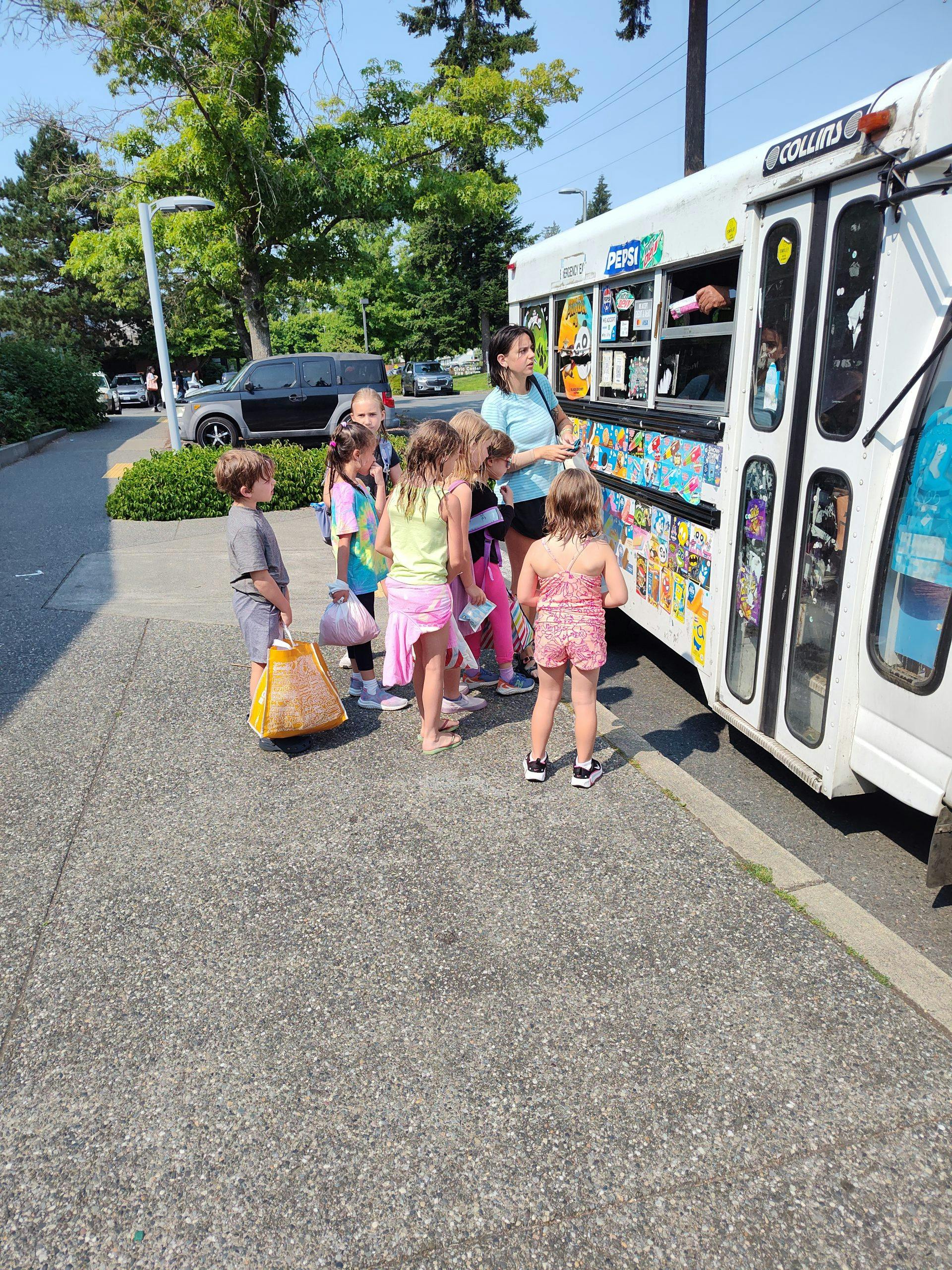 A group of children and a person waiting by an ice cream truck