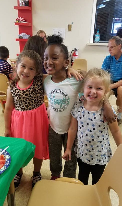 Three children standing together with arms around each other