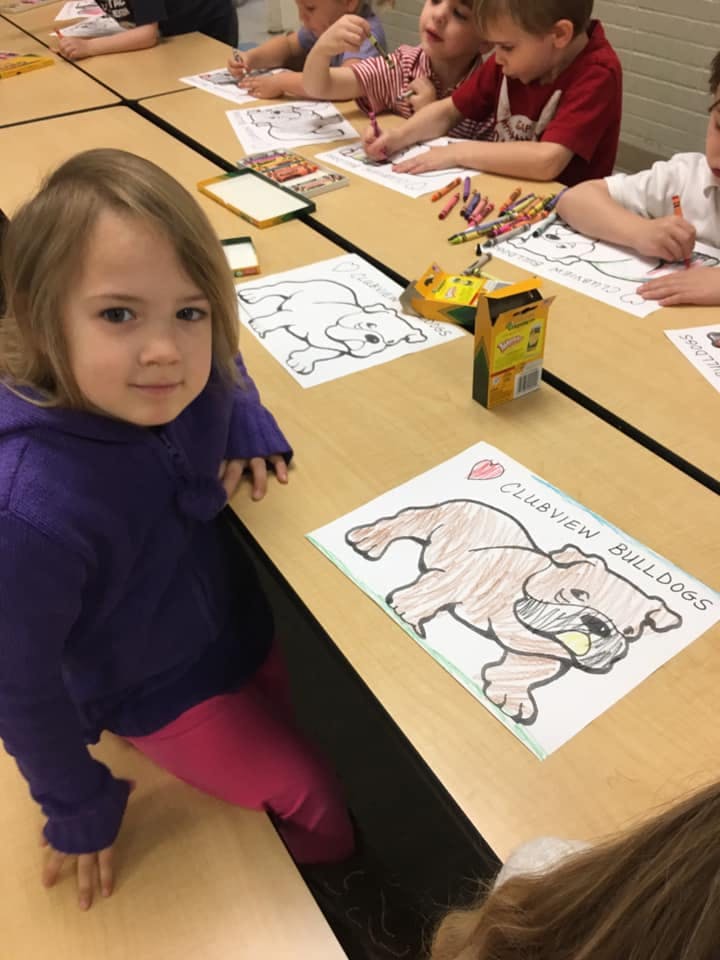 Child coloring at a table with other children