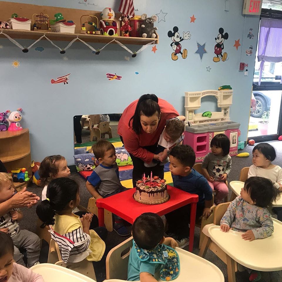 Person holding a child blowing out candles on a cake surrounded by children