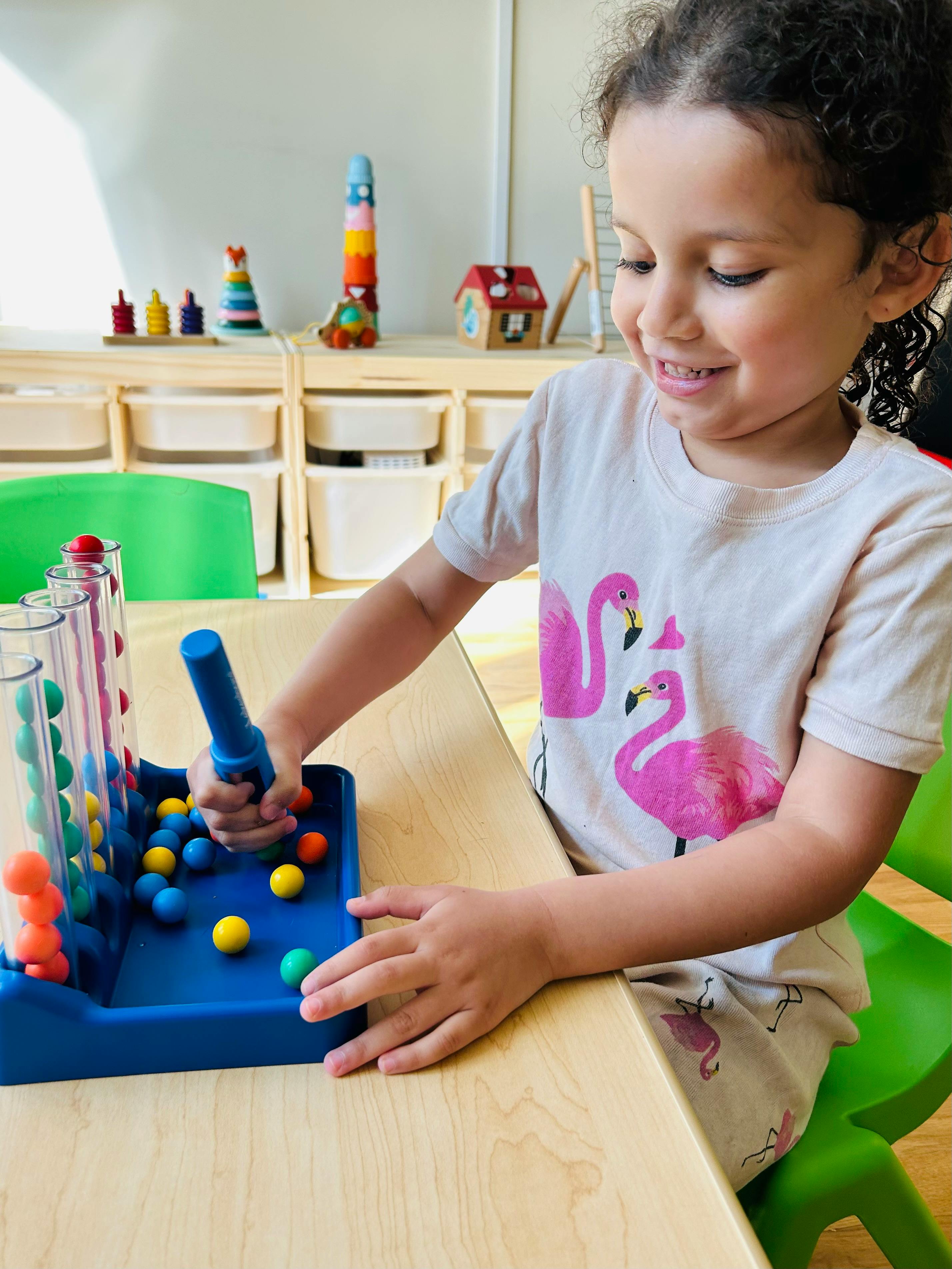 Child playing with a colorful ball sorting toy at a table