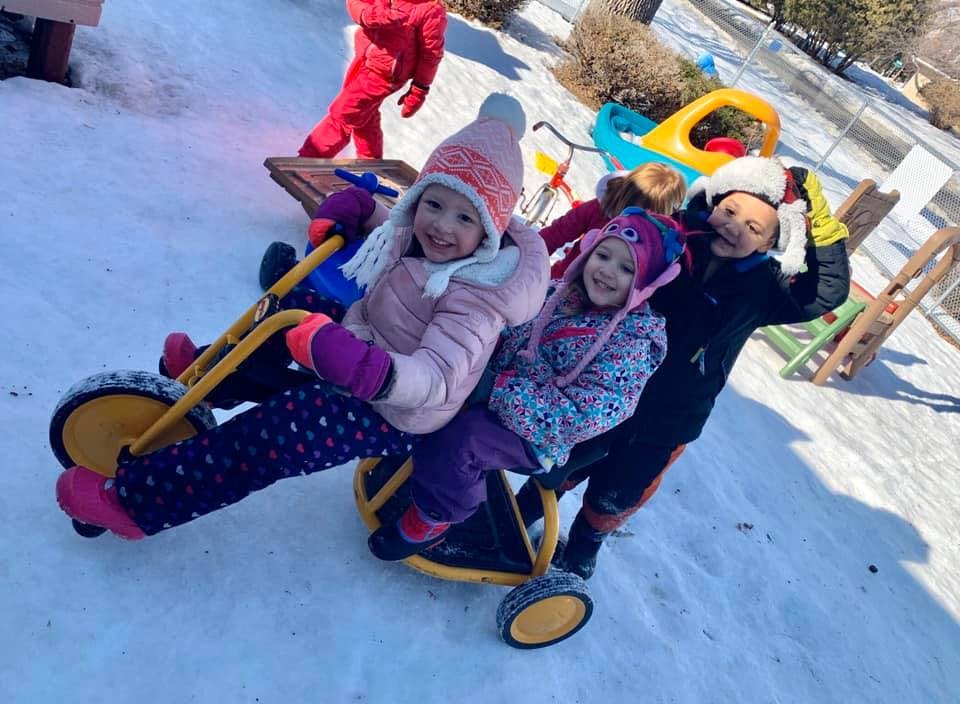 Three children on a tricycle in the snow