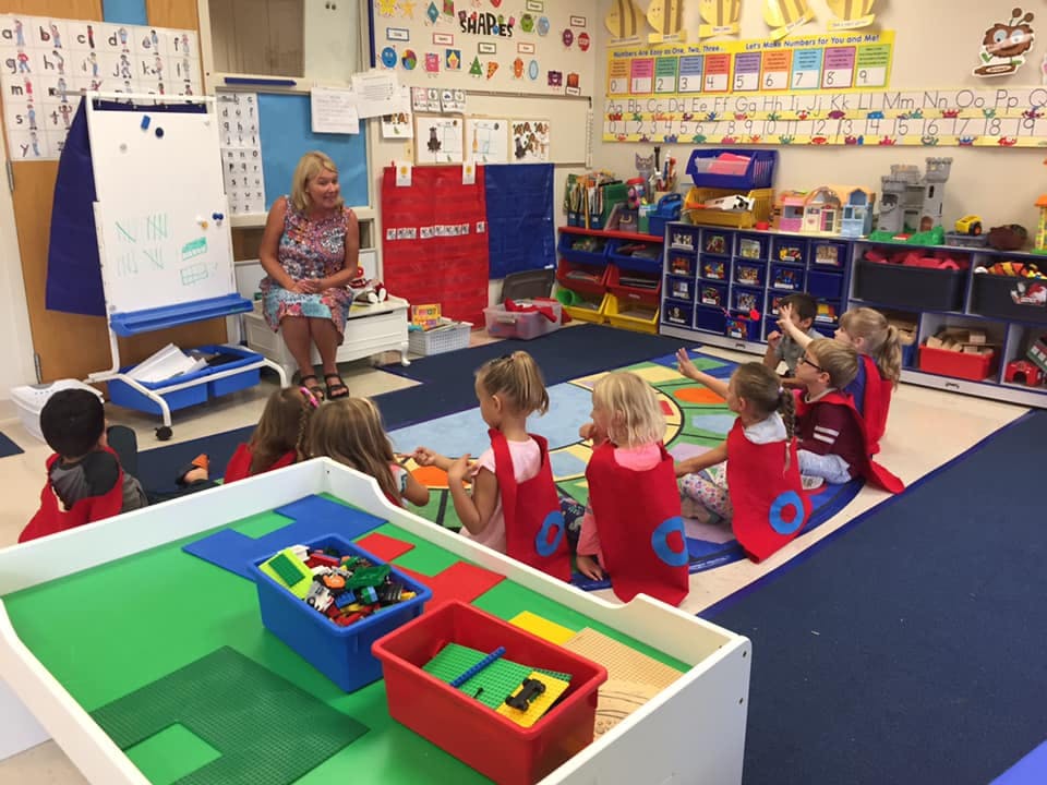 Adult and children sitting on floor in classroom