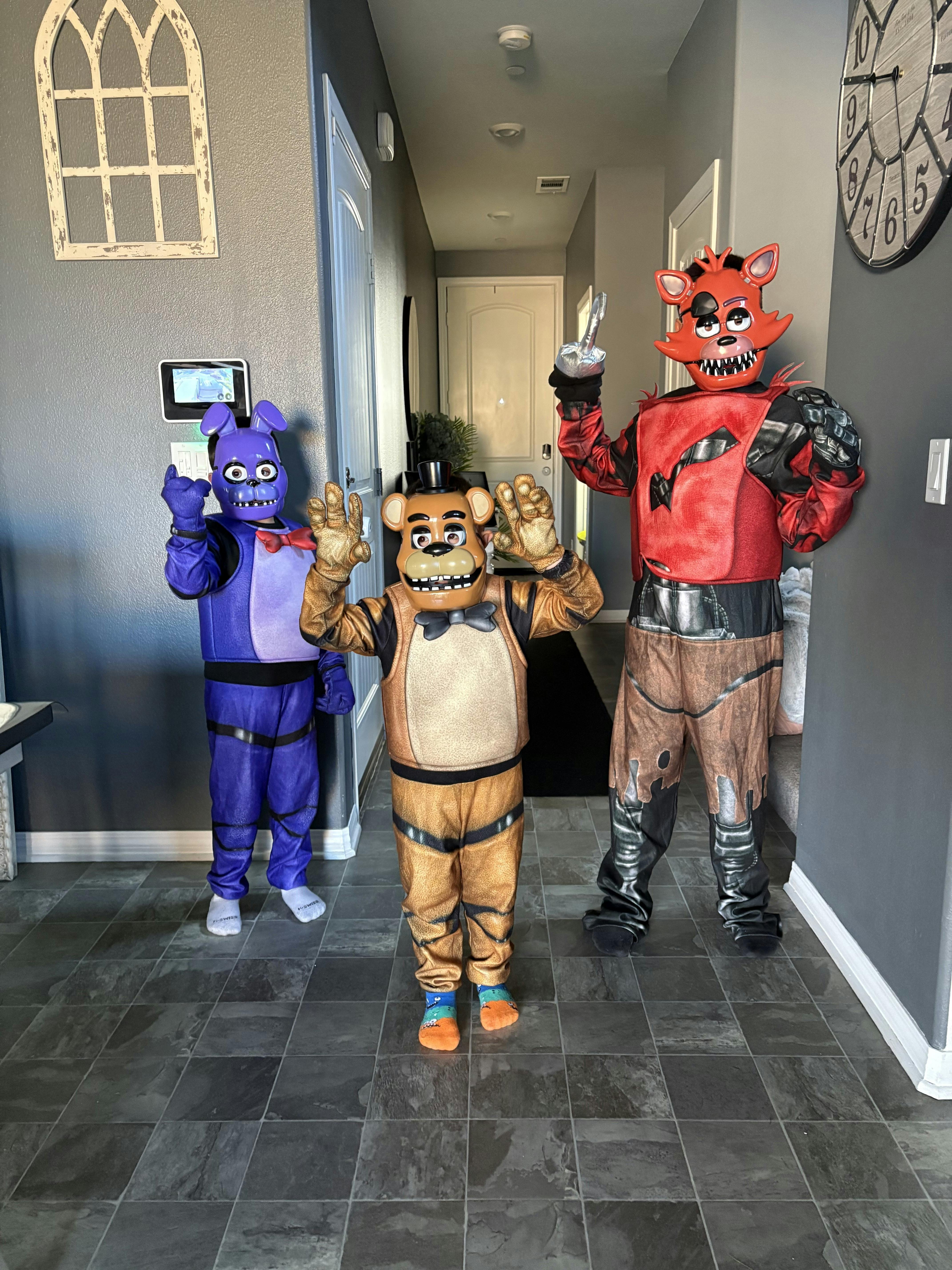 Three children in Five Nights at Freddy's character costumes standing in a hall