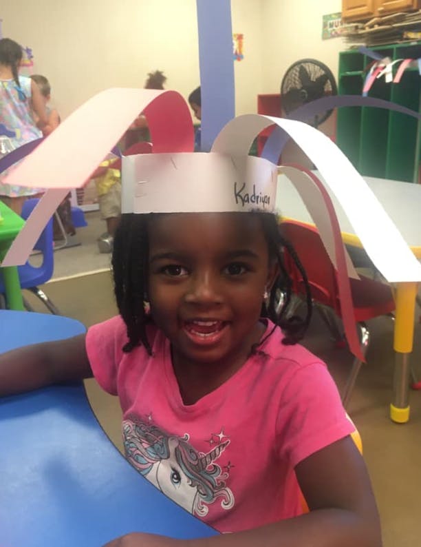 Child wearing a paper hat with "Kadrian" written on it