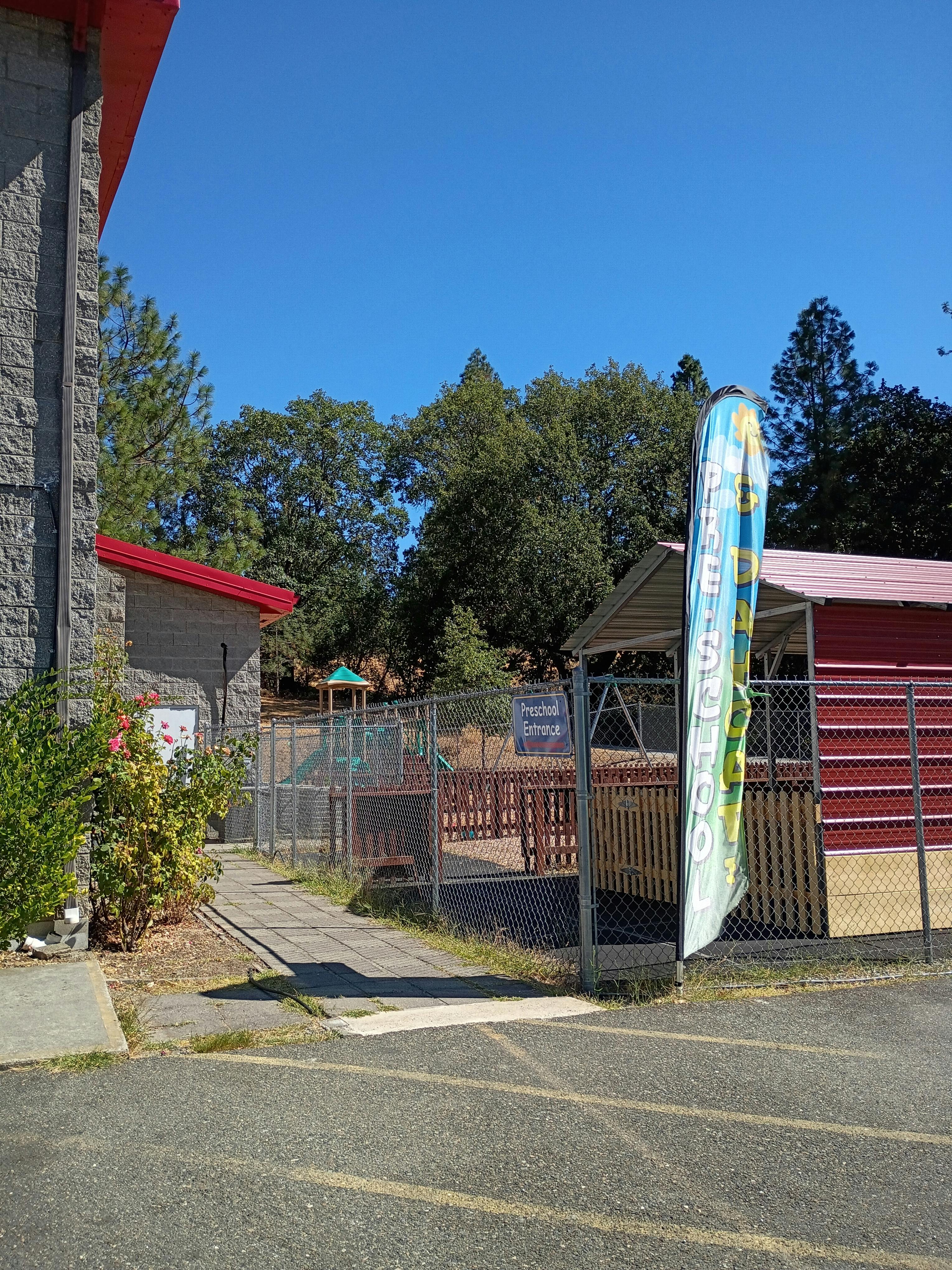 Playground with a chain-link fence and a building with a red roof