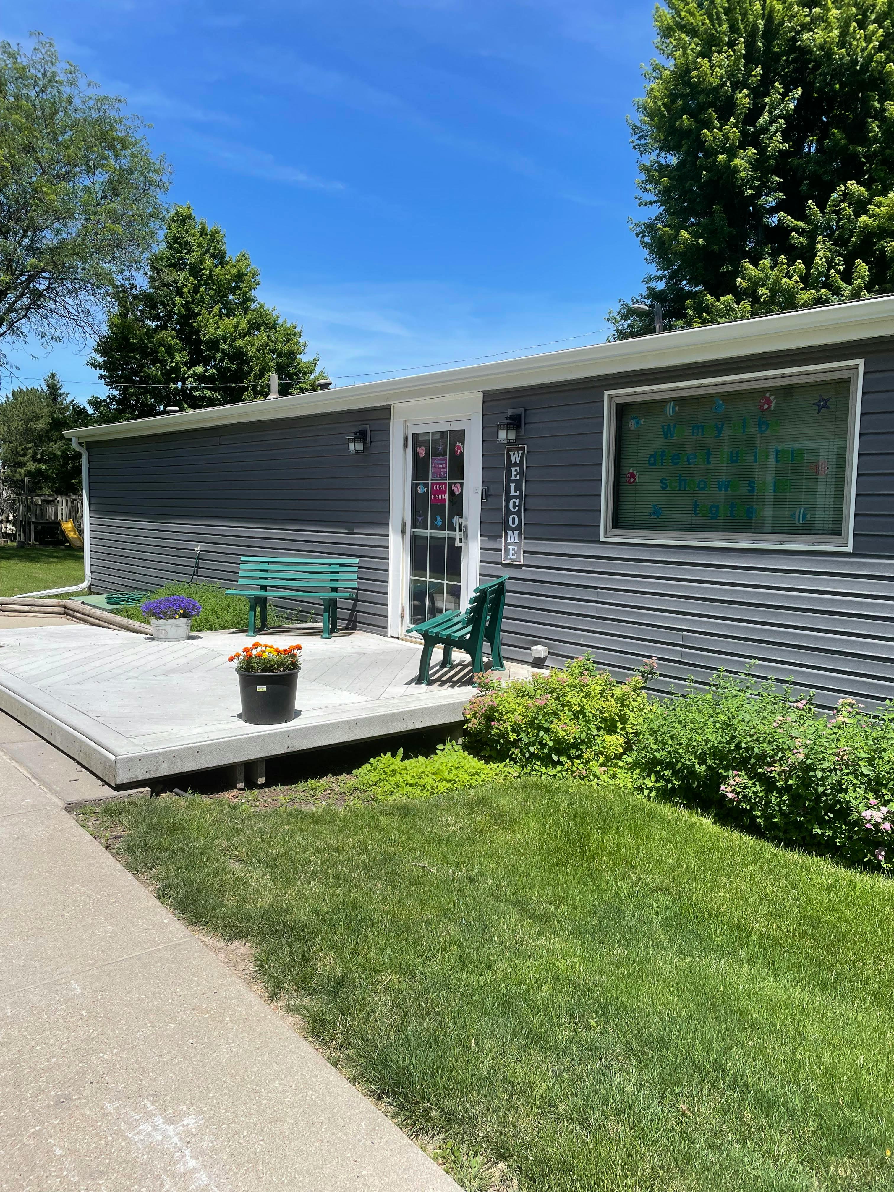 Building exterior with a concrete patio and green benches