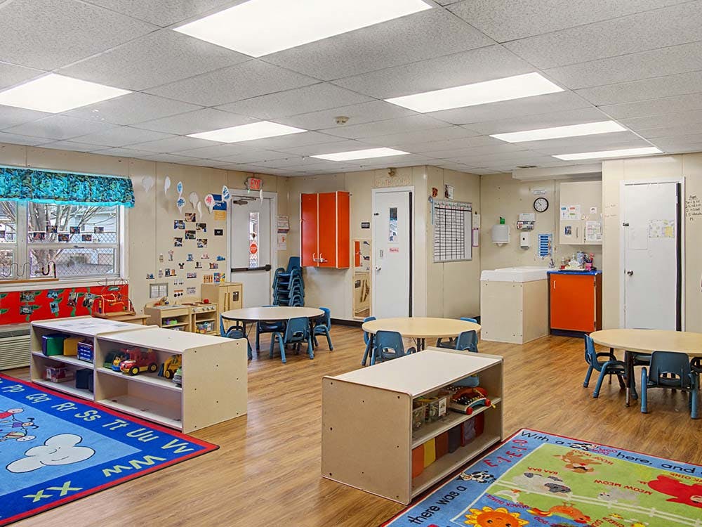 Empty colorful preschool classroom with small tables and chairs