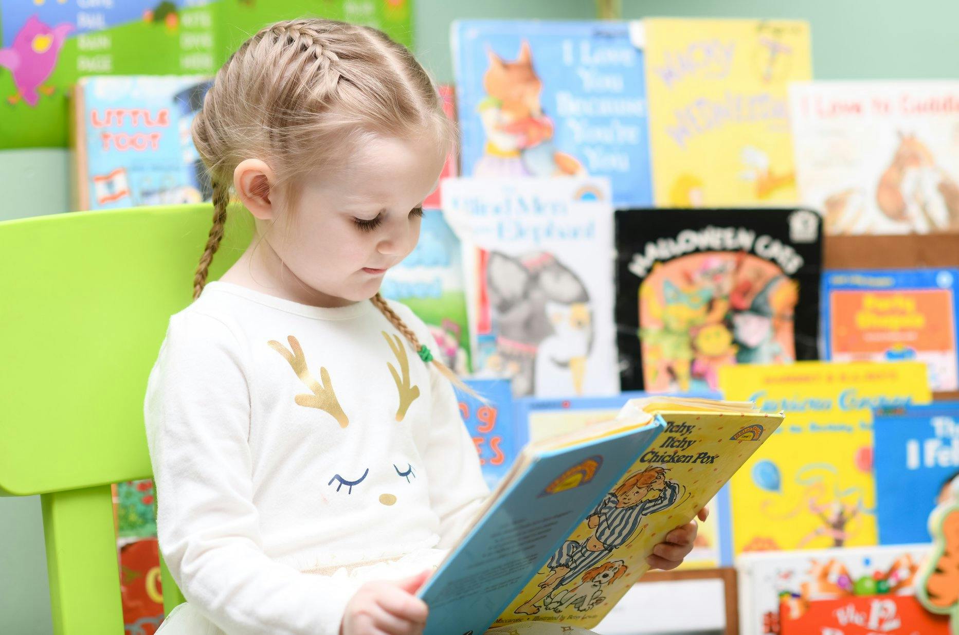 Child with braided hair reading a book in a classroom