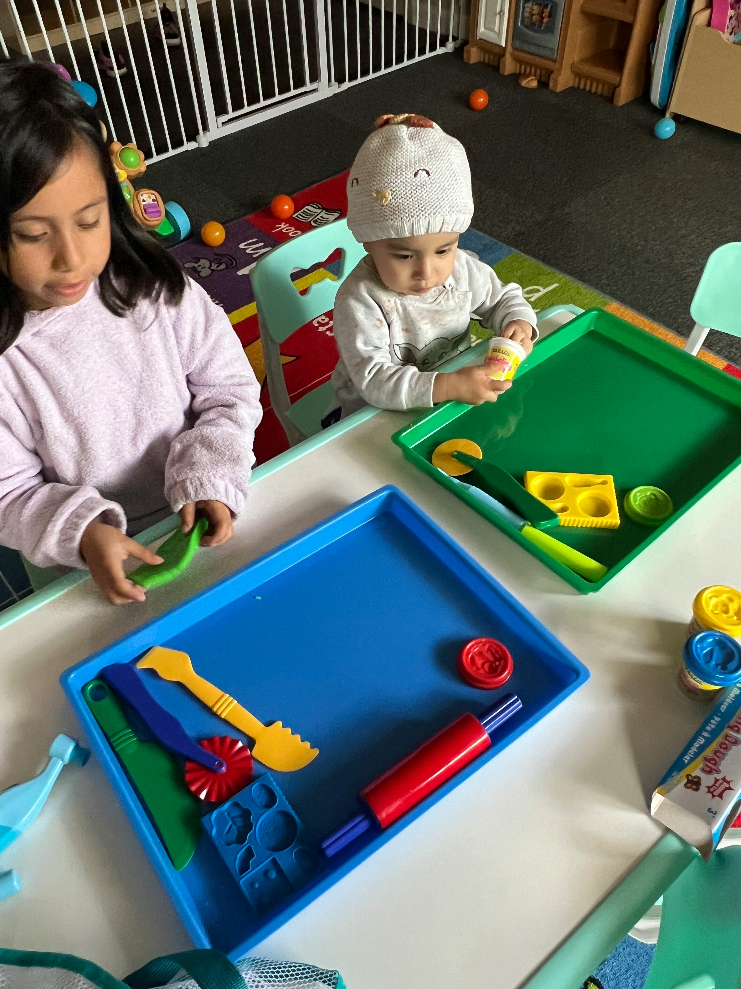 Child and baby playing with colorful toys in trays