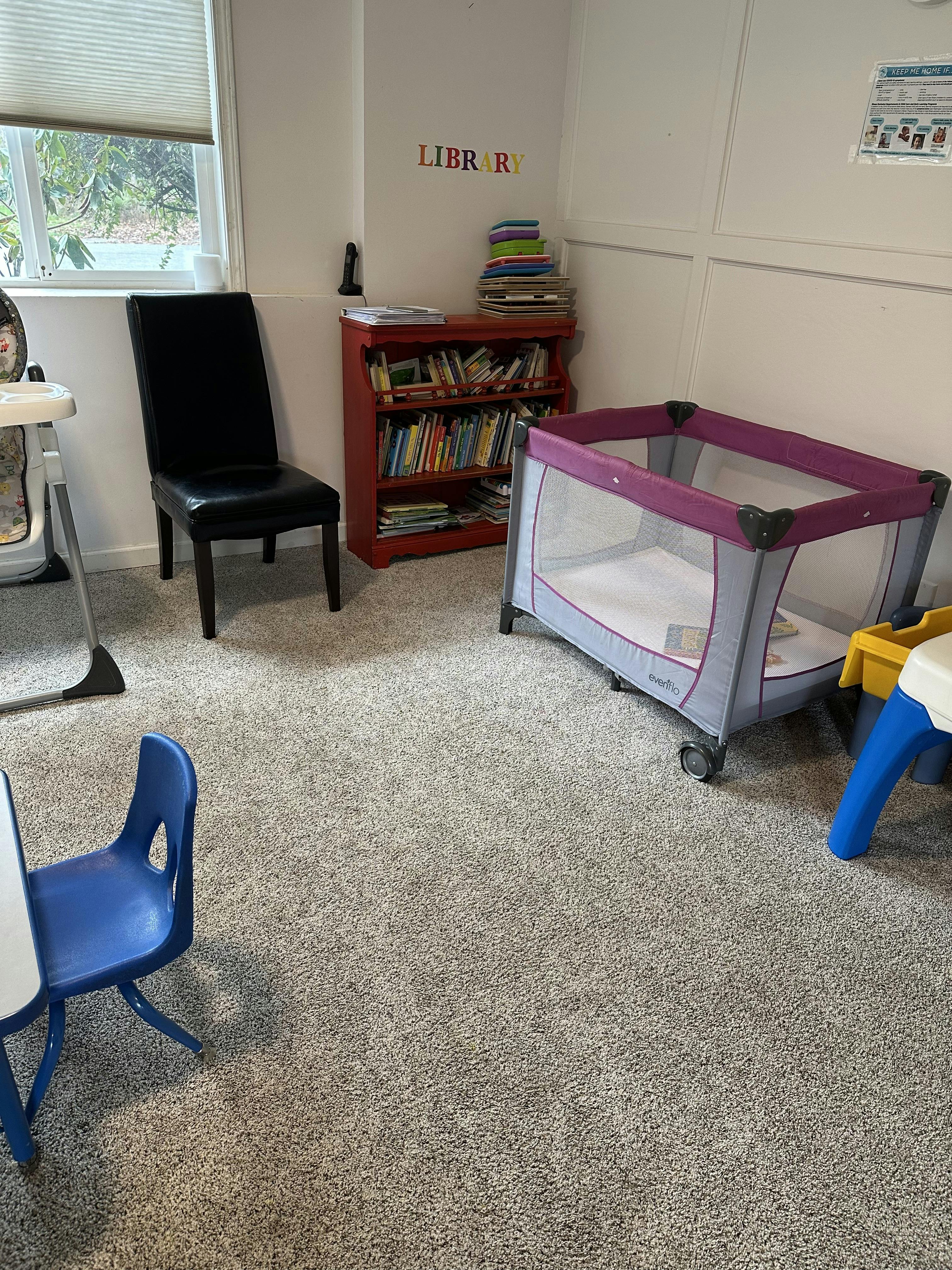 Playpen, bookshelf, and child's chair in a room