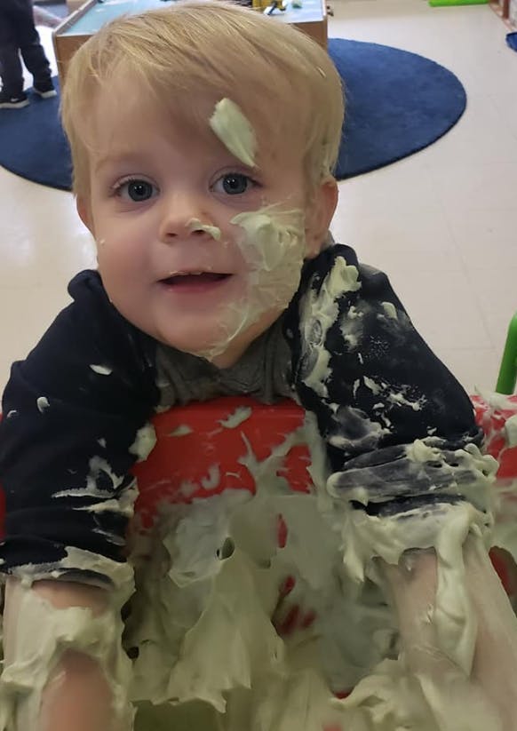 Child covered in light green foam or white foam or yellow substance
