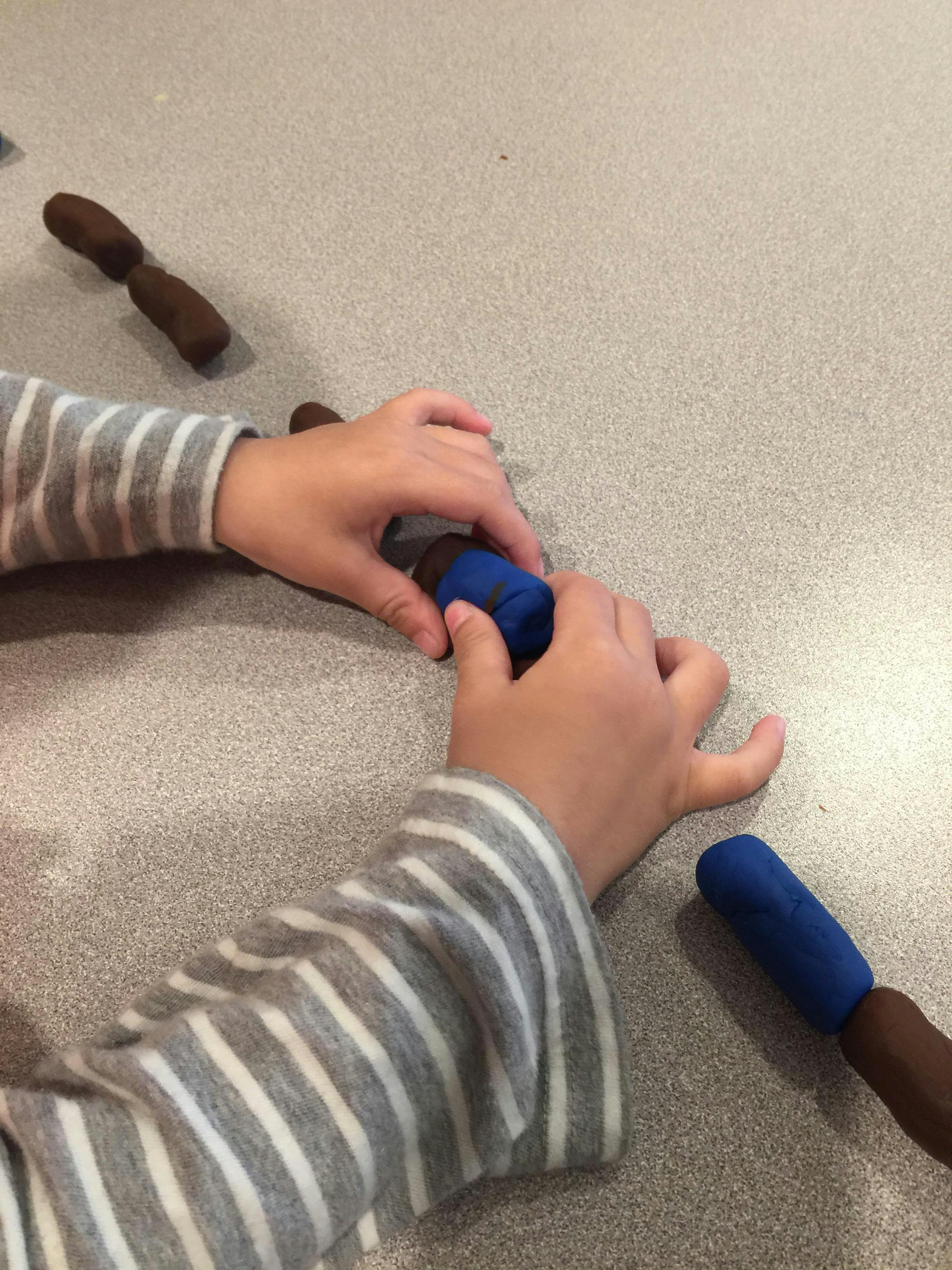 Child's hands playing with blue and brown modeling clay