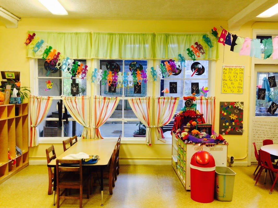 Classroom with windows, curtains, and a long table with chairs