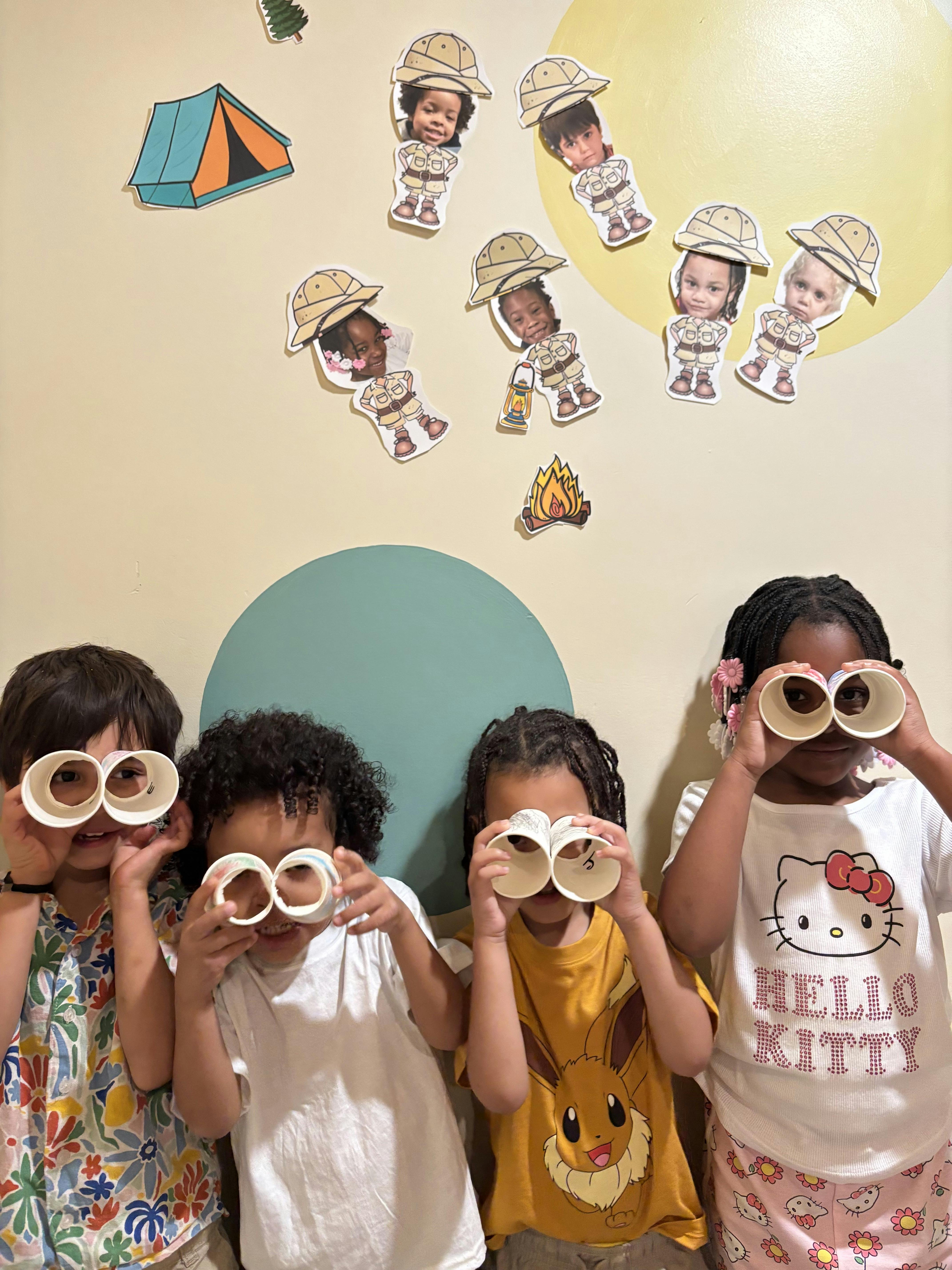 Four children holding paper cups to their eyes to mimic binoculars