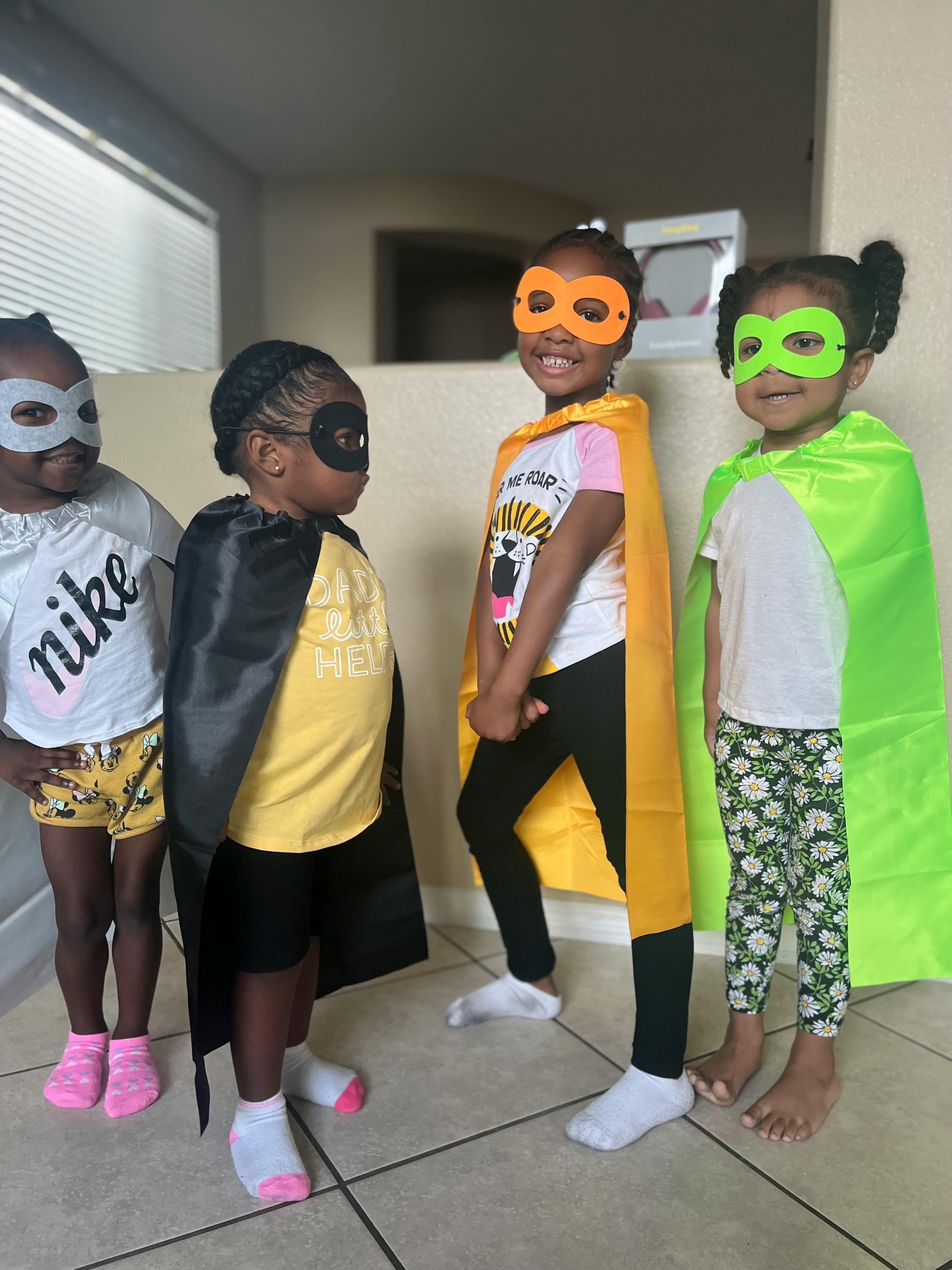 Four children wearing superhero masks and capes