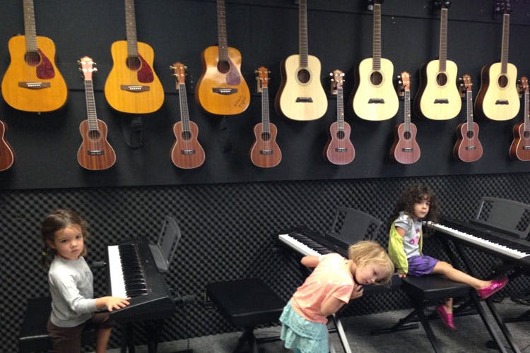 Three children with keyboards and guitars hanging on a wall