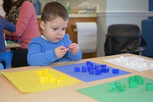Child playing with colorful building blocks at a table