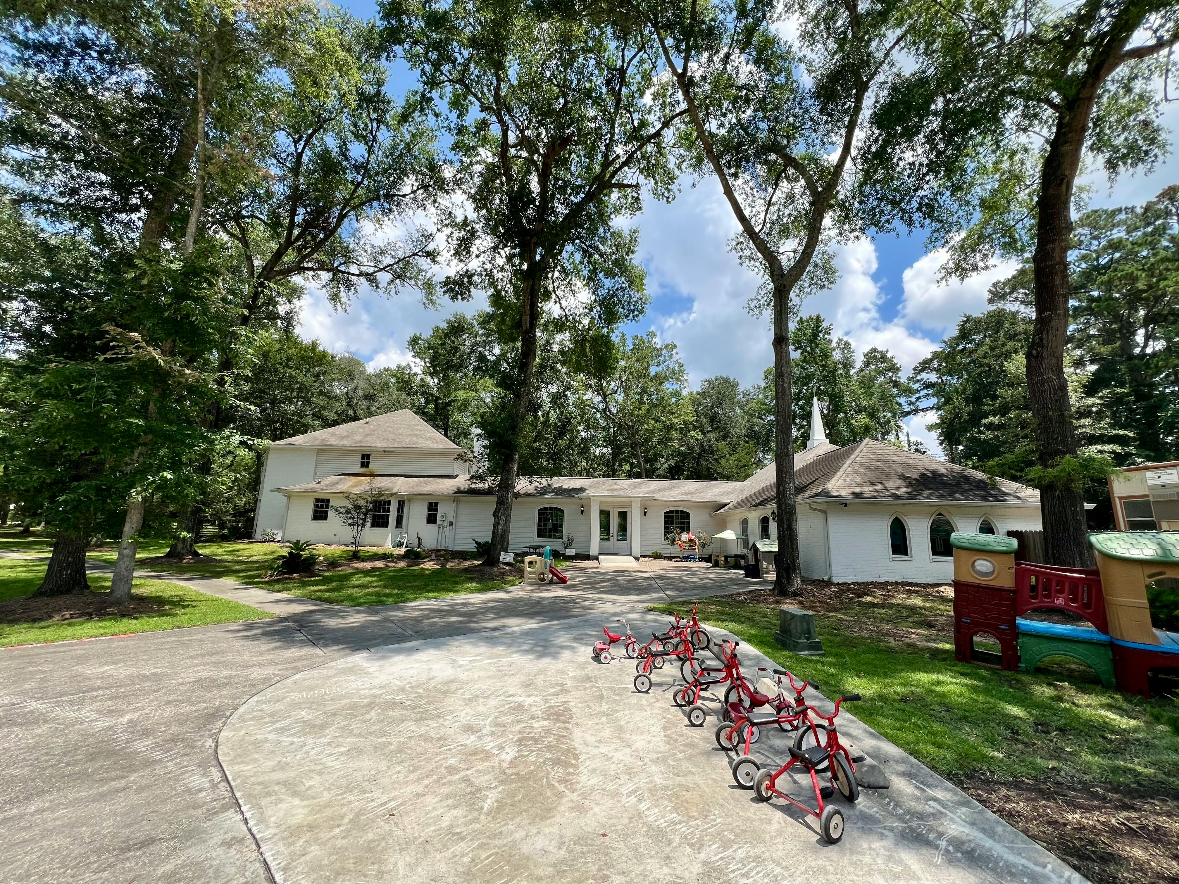 Building with a row of tricycles on a paved area in front