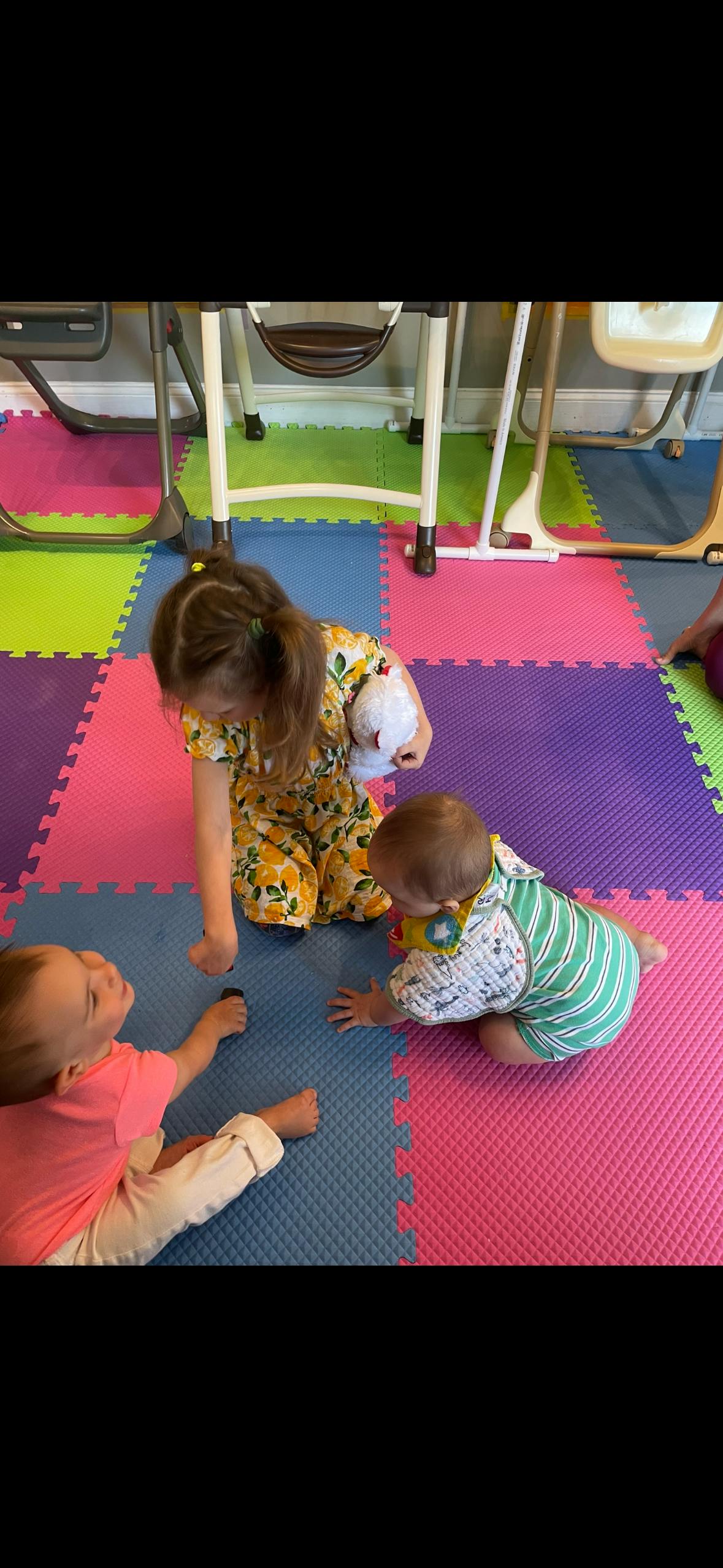 Child kneeling on colorful mat with two babies