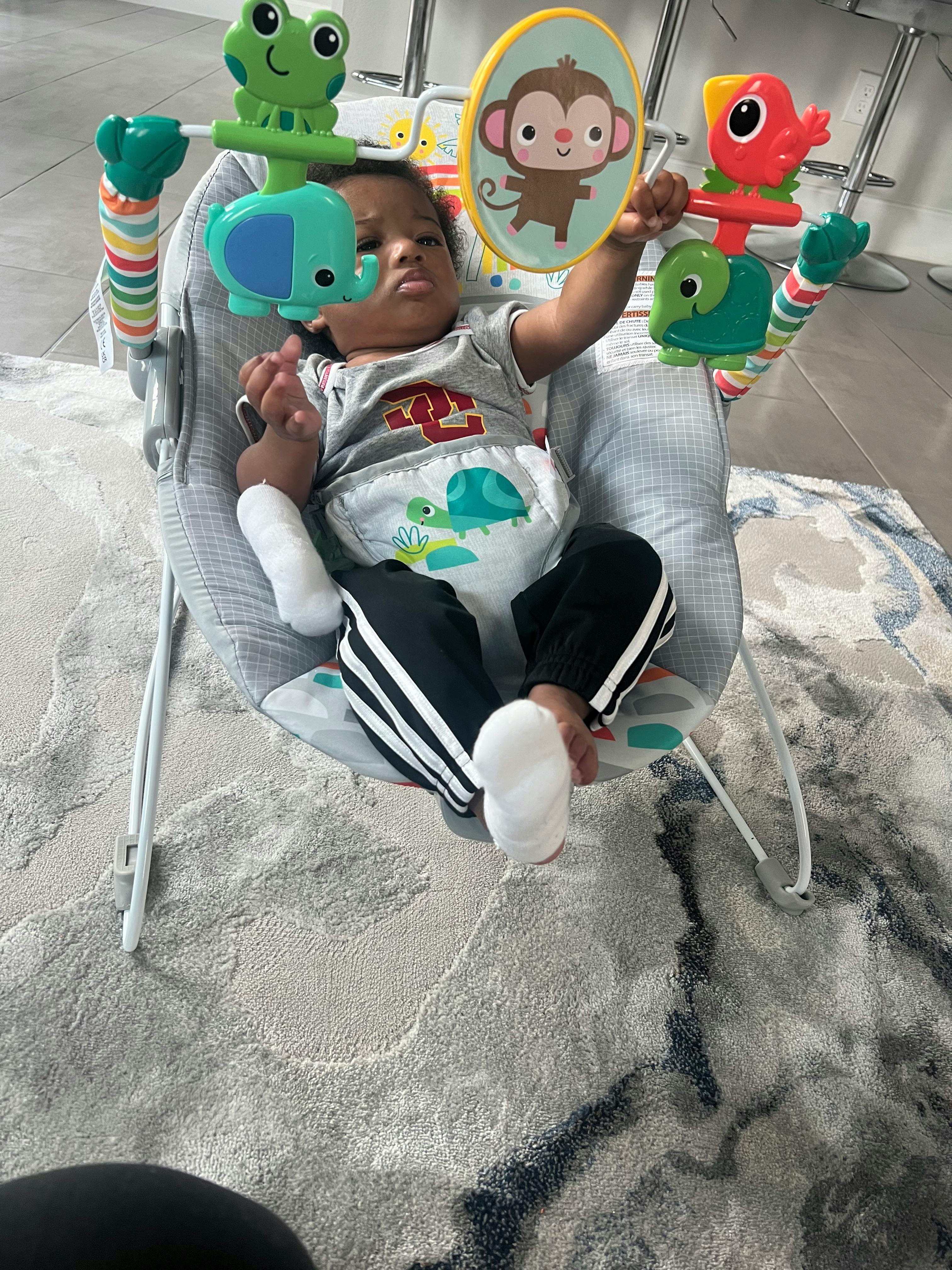 Child in a baby bouncer with hanging toys