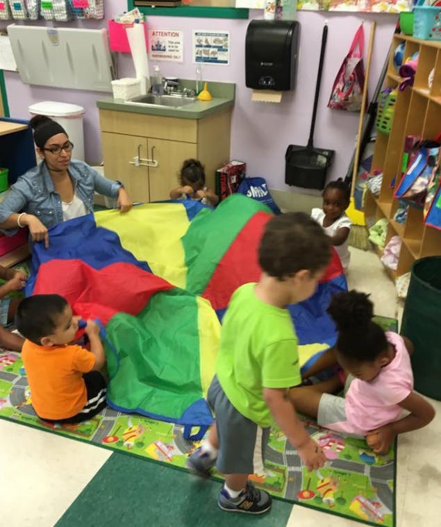 Adult and children playing with a colorful parachute on the floor