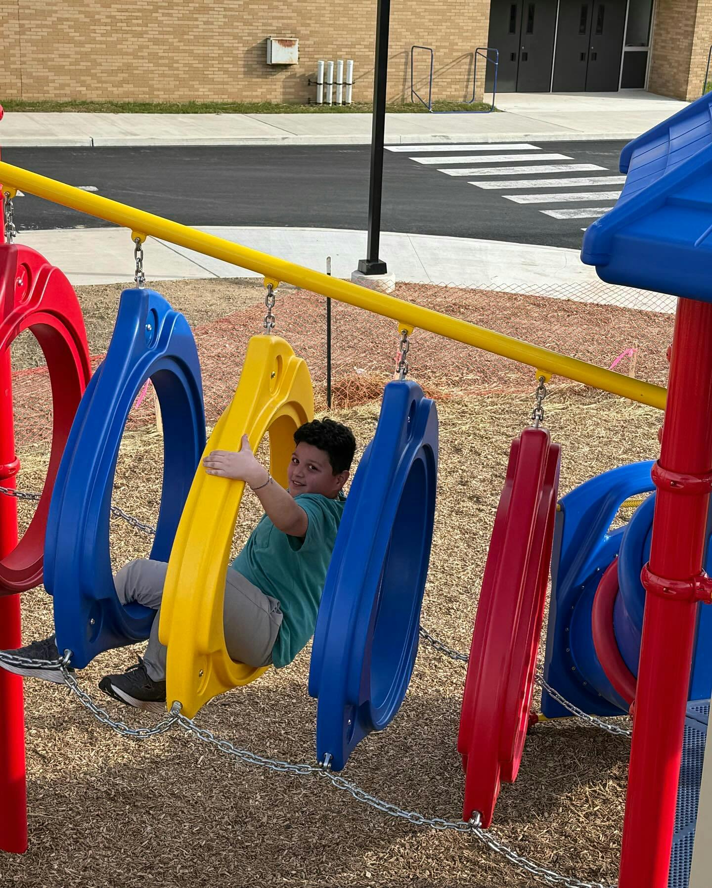 Child sitting in a yellow swing on a playground