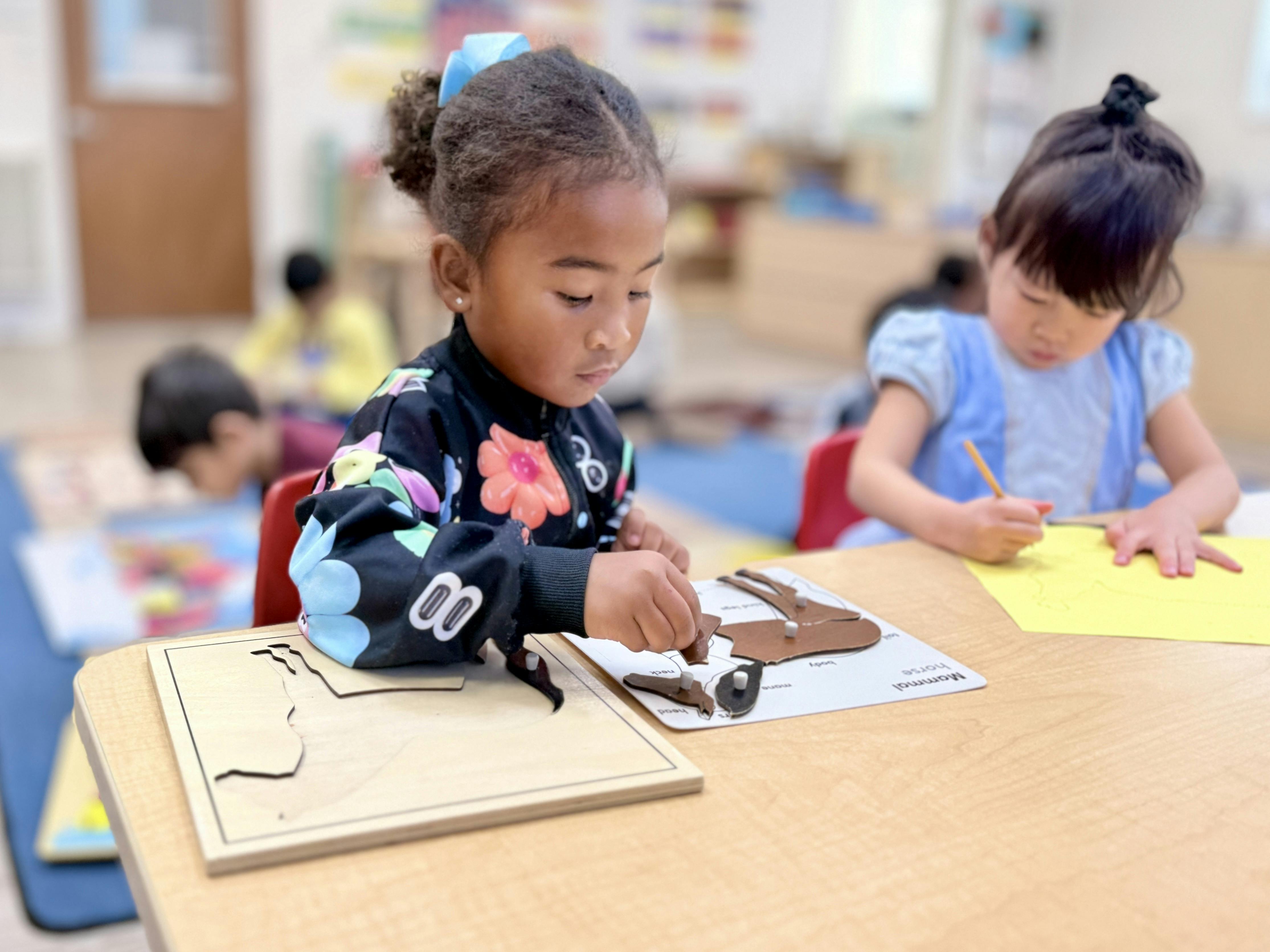 Child assembling a horse puzzle at a table in a classroom