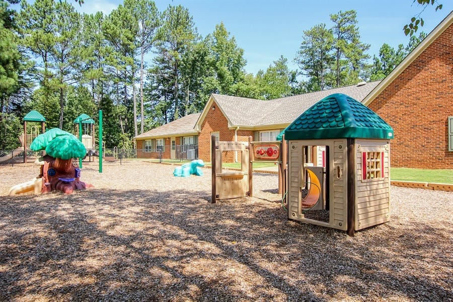 Outdoor playground with play structures and a small playhouse