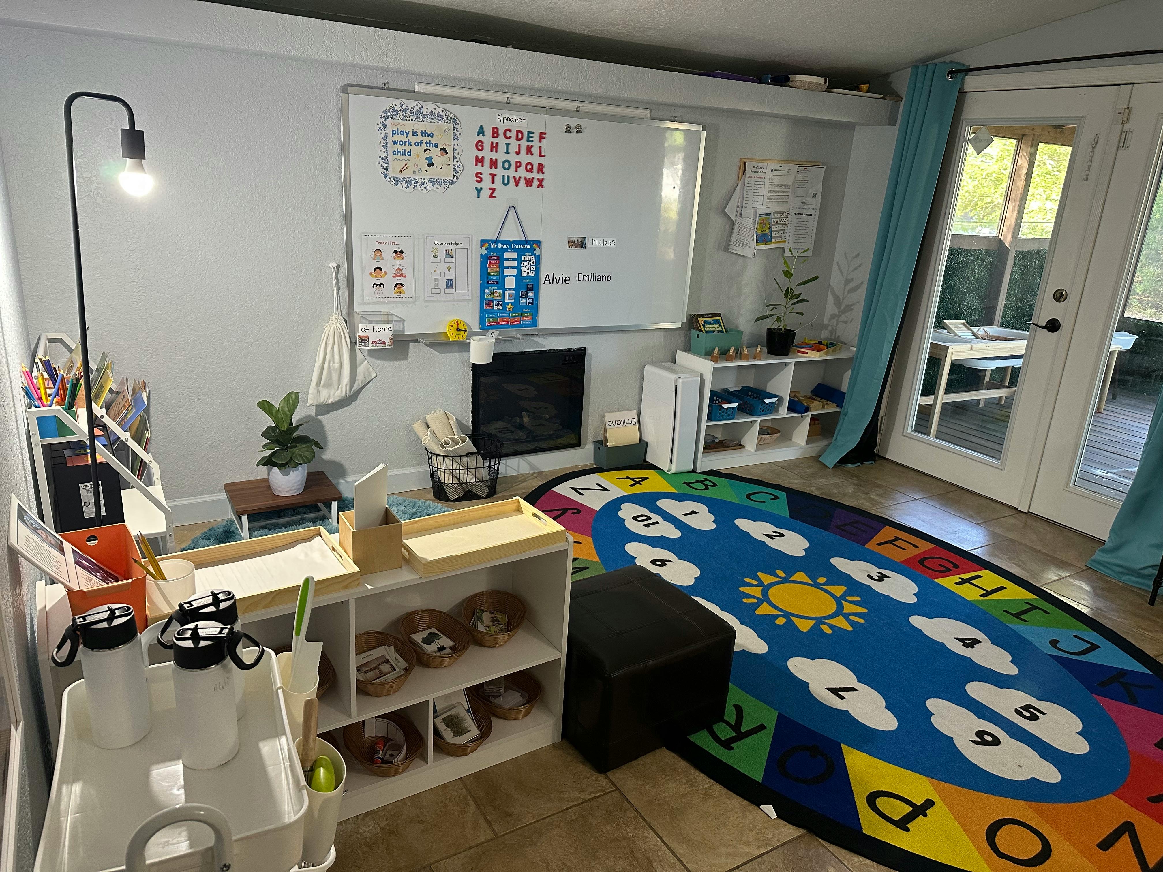 Classroom with a whiteboard, colorful rug, and shelves with shelves and tables