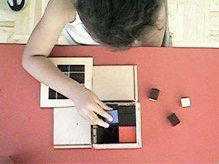 Child playing with a wooden puzzle on a red surface