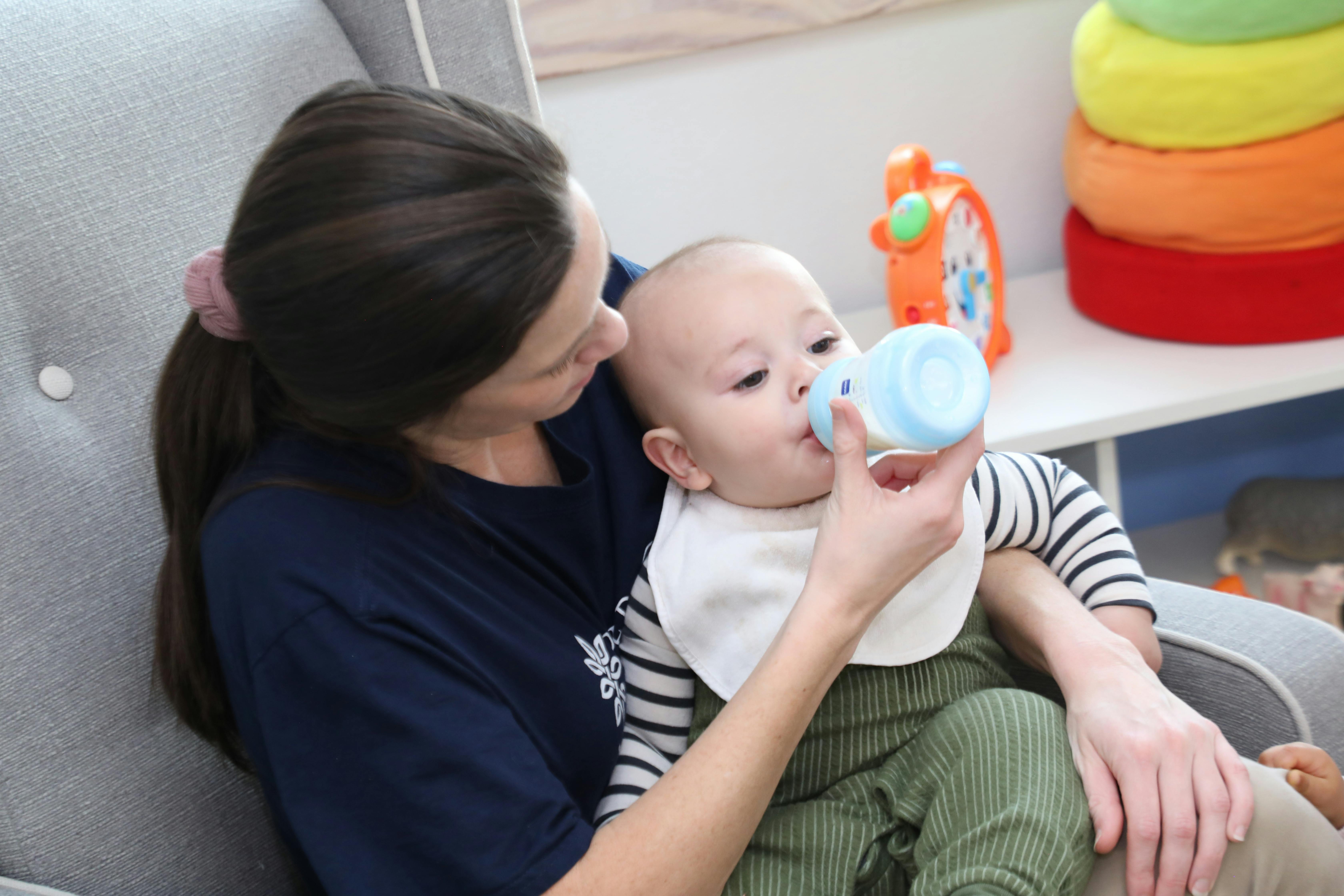 Person feeding a baby from a bottle