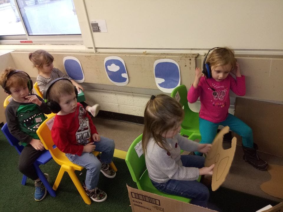 Children playing in a pretend airplane with headphones