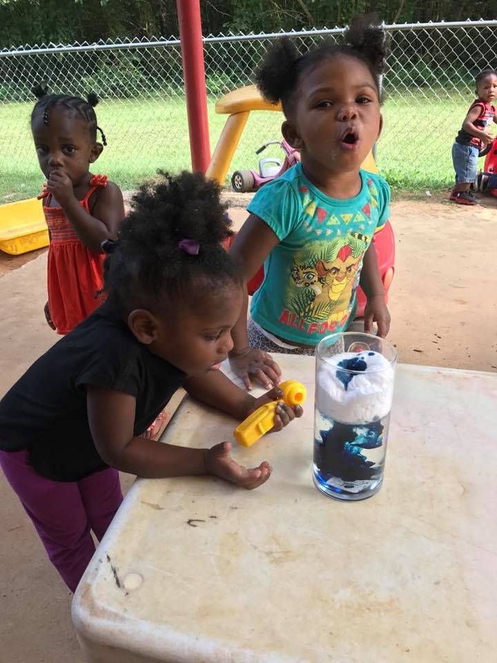 Three children observing a science experiment in a glass