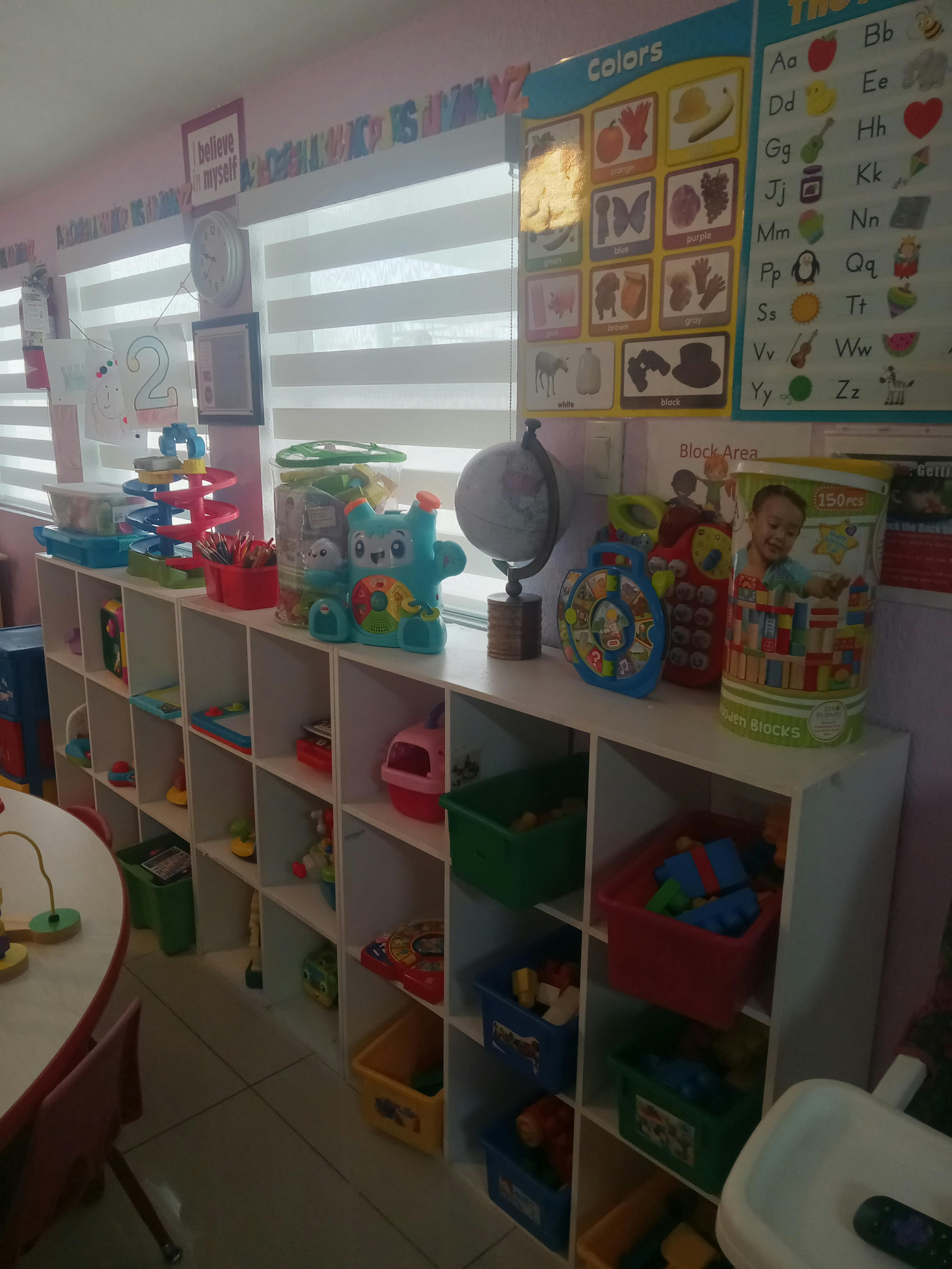 A playroom shelf with bins containing various toys and an educational wall chart