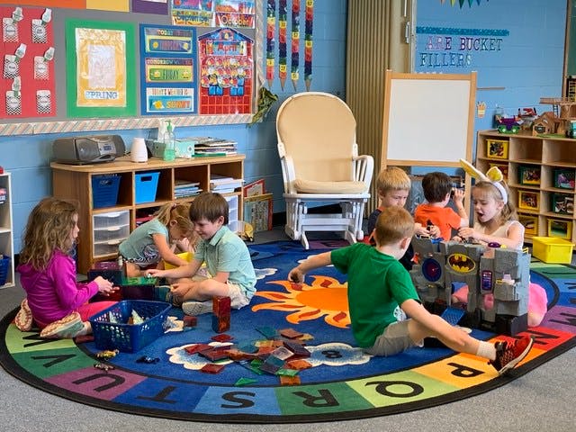 Children playing on a rug in a classroom