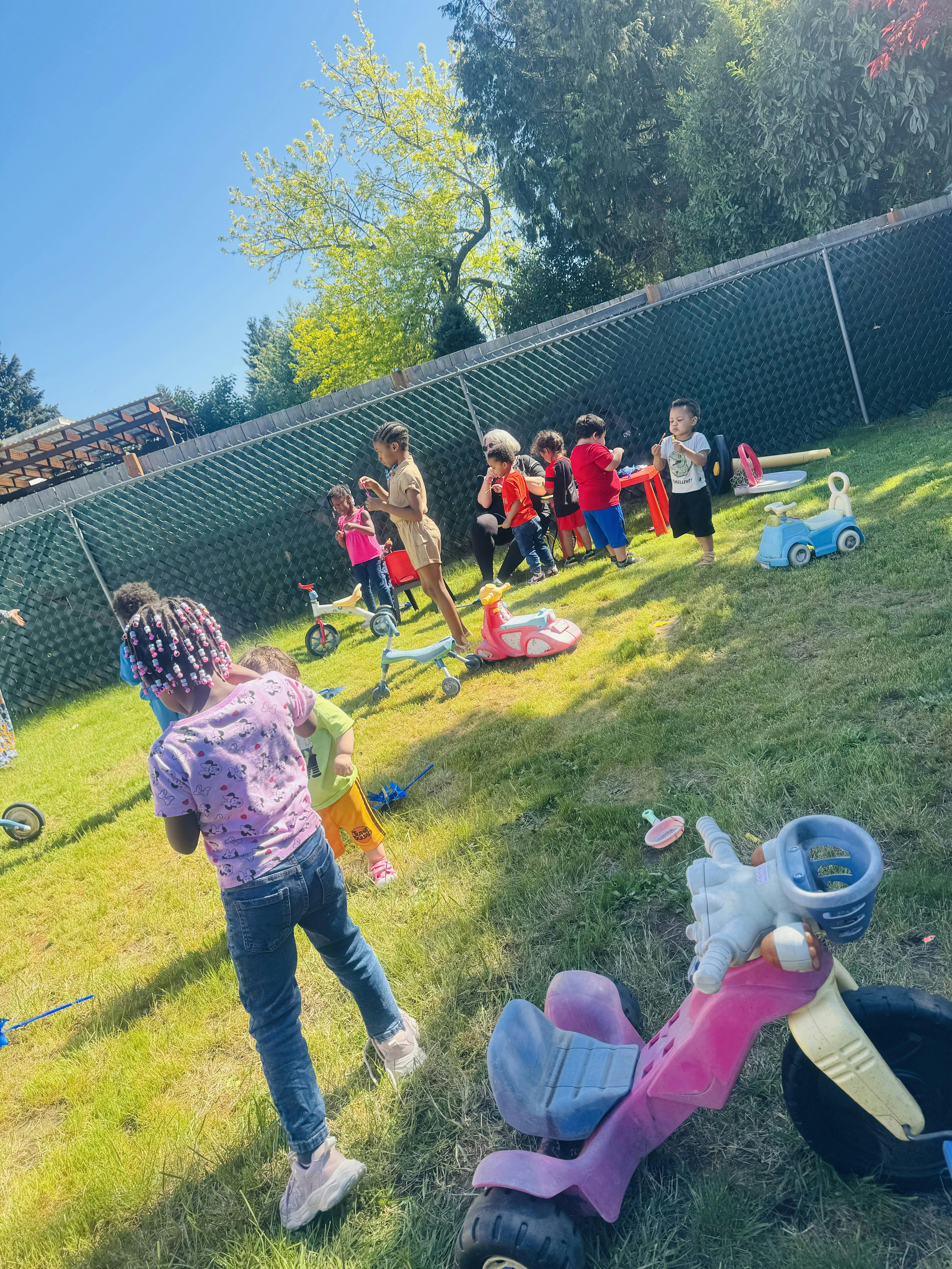 Children playing outdoors in a grassy area with toys
